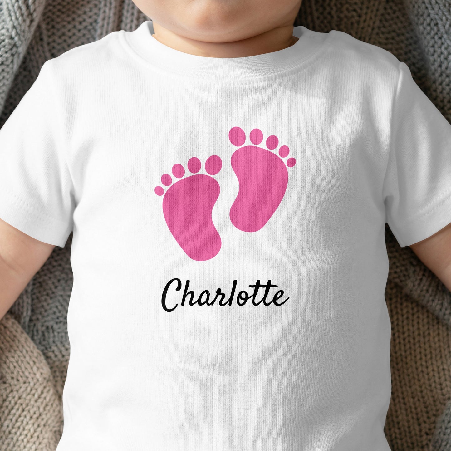 Pink baby footprints on a white t-shirt with "Charlotte" text.