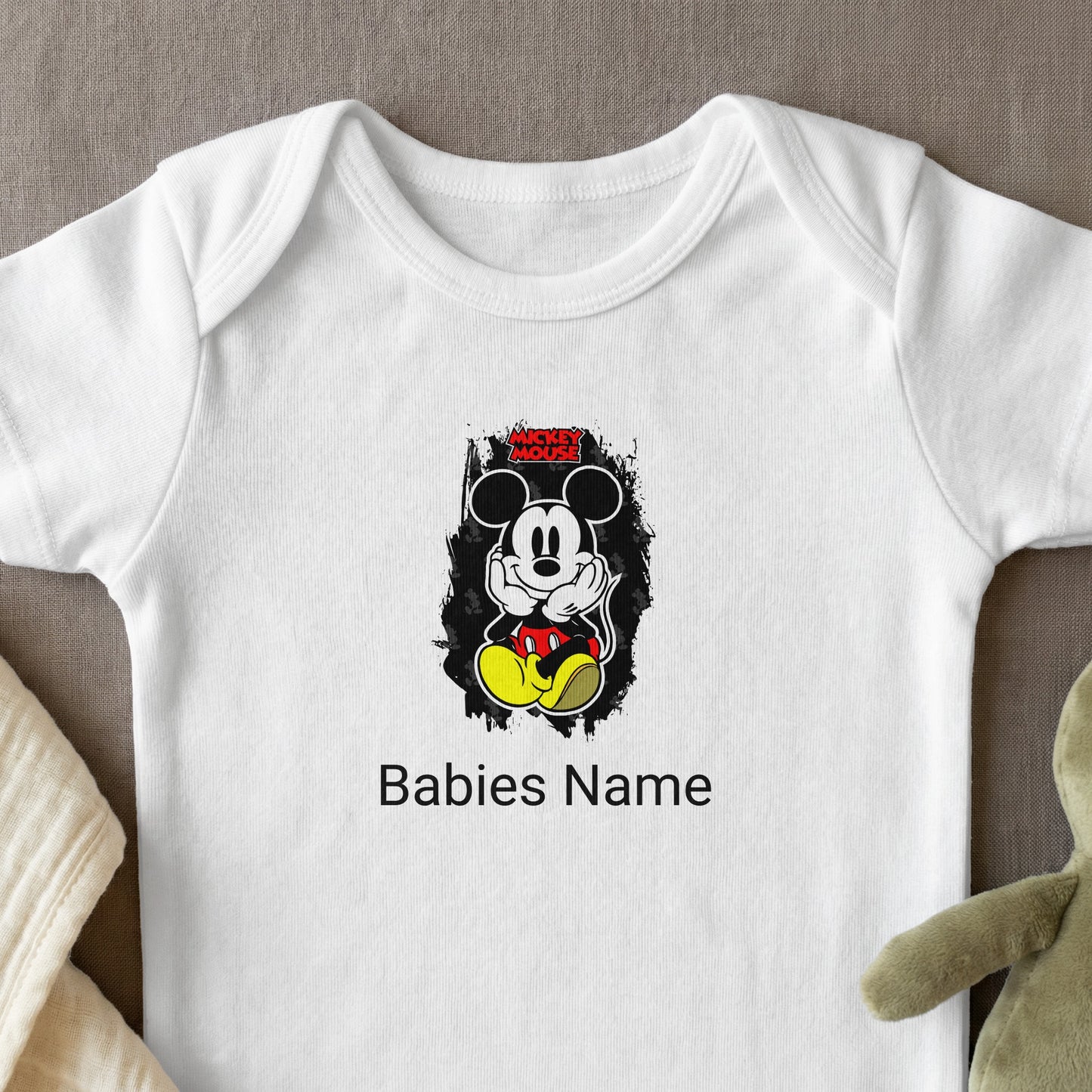 White baby onesie with Mickey Mouse graphic and customizable "Babies Name" text.