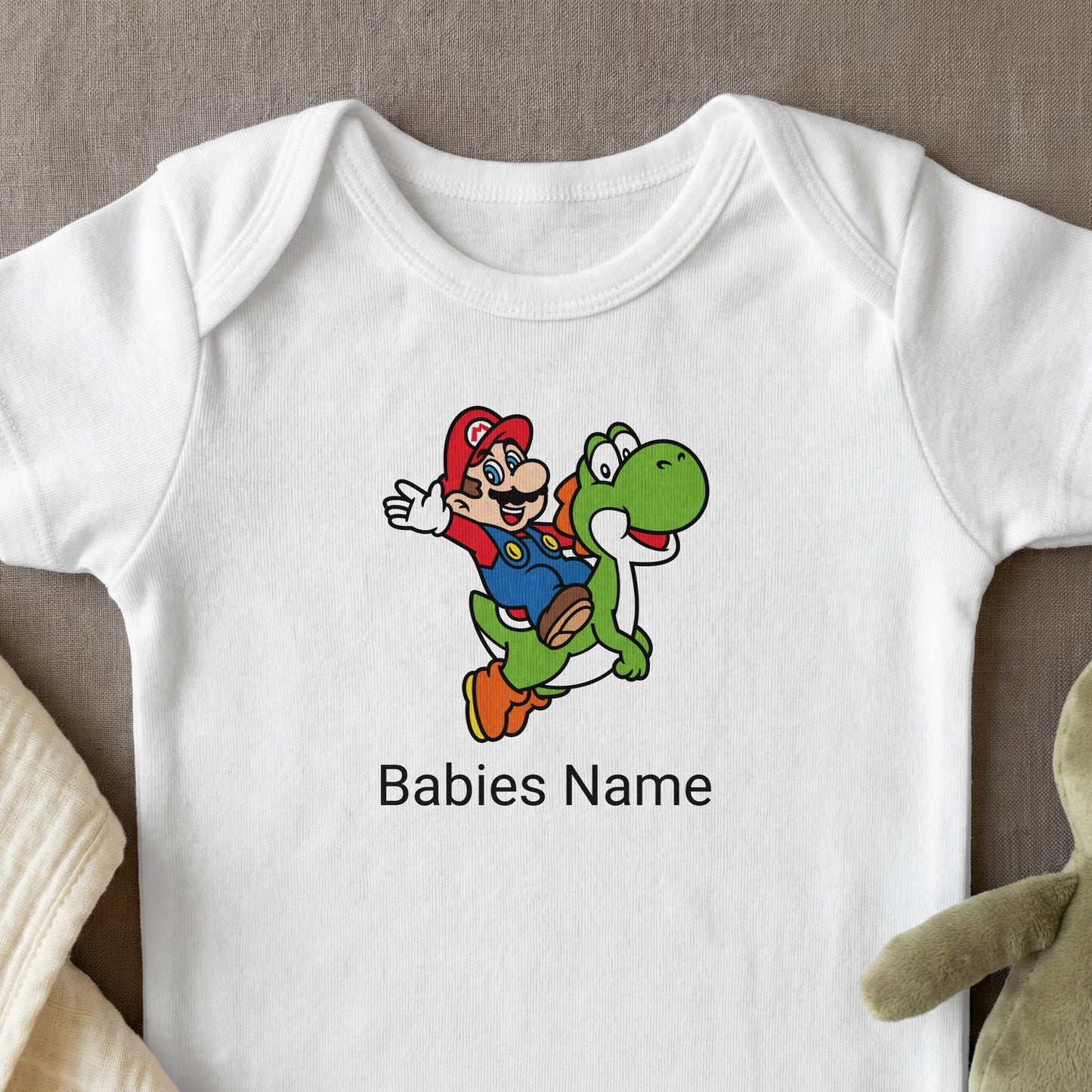 Mario riding Yoshi on a white baby onesie with text "Babies Name".