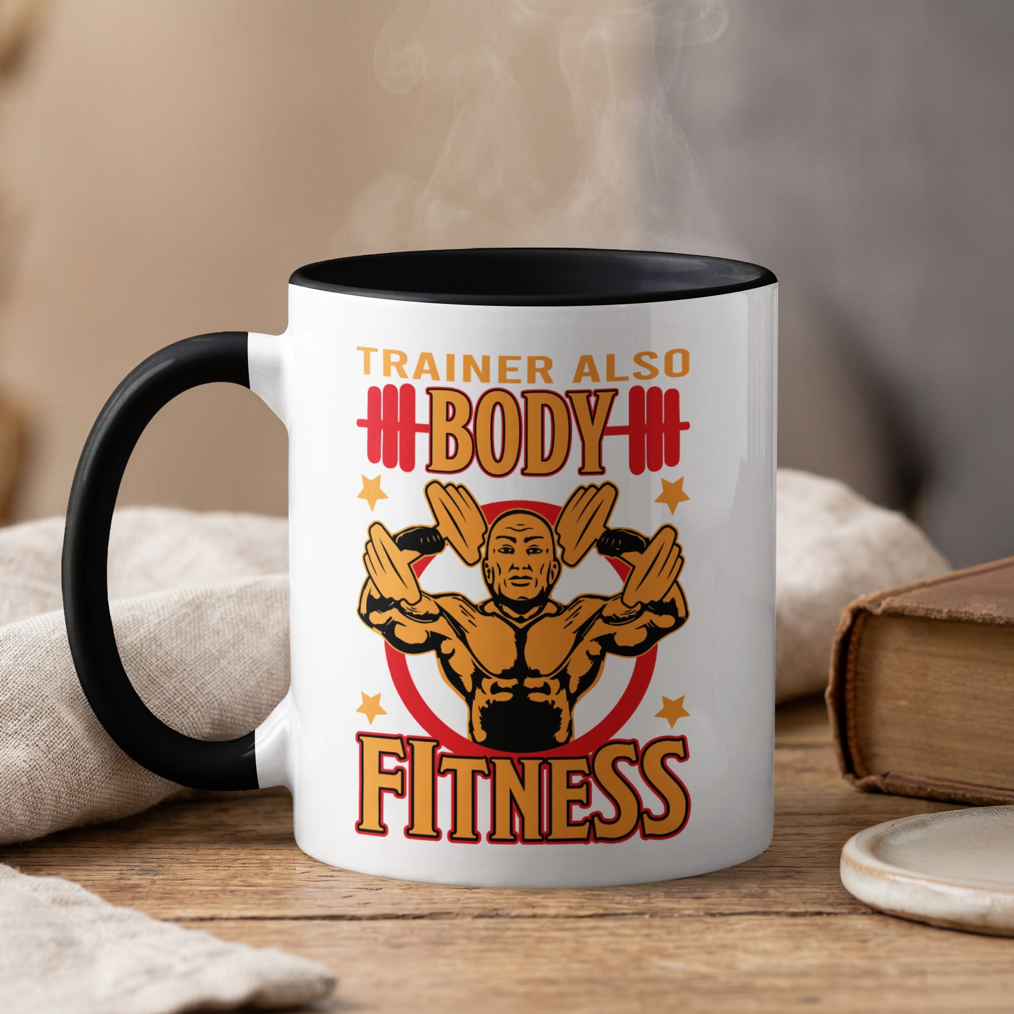 White mug with black rim, reads "TRAINER ALSO BODY FITNESS" with muscular man graphic.