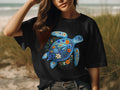 Black t-shirt with a blue sea turtle decorated with colorful floral patterns.