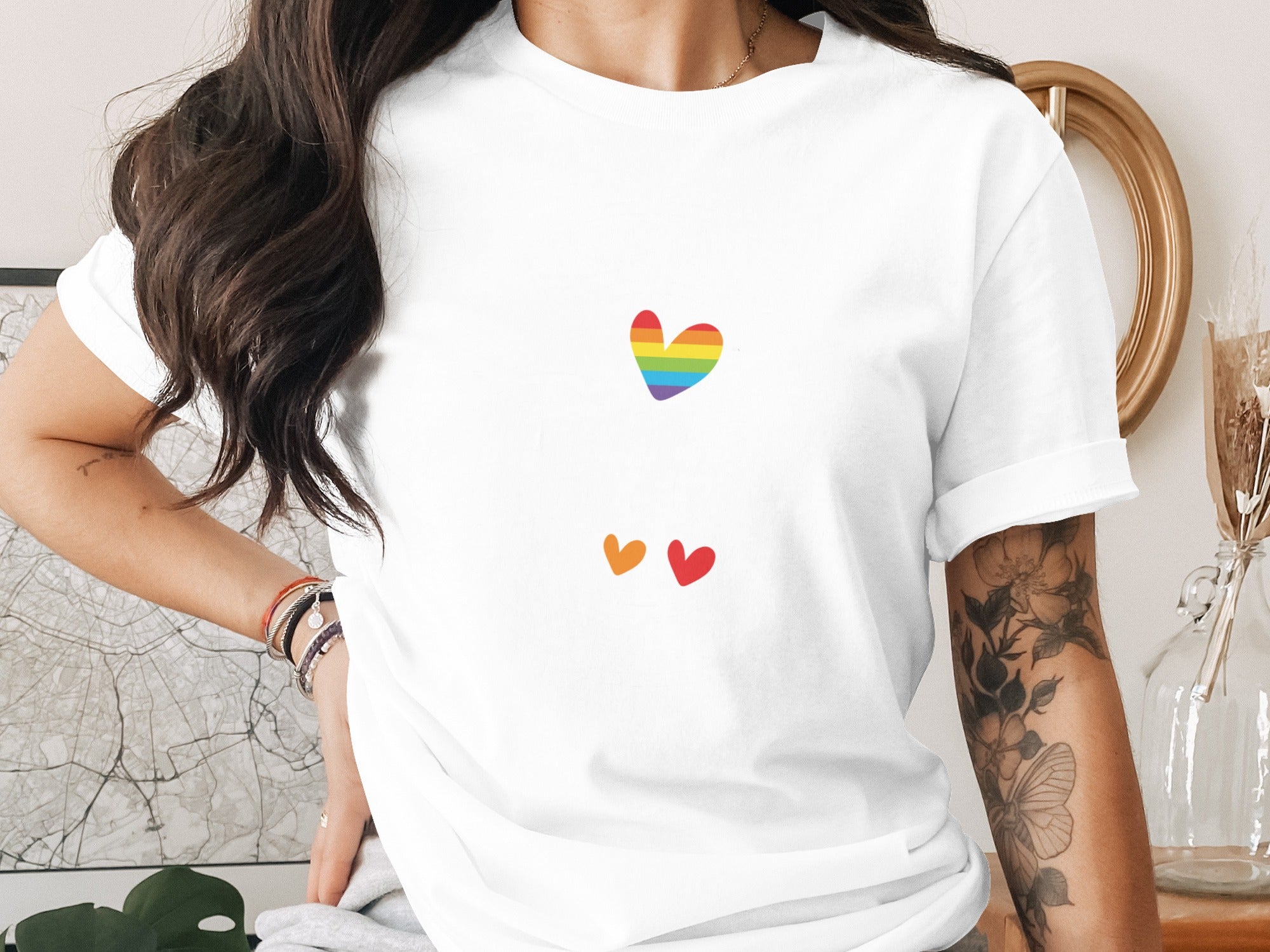 White t-shirt with rainbow heart and two smaller red and orange hearts.