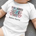 White baby onesie with "THE LADIES LOVE ME" text and heart graphics.