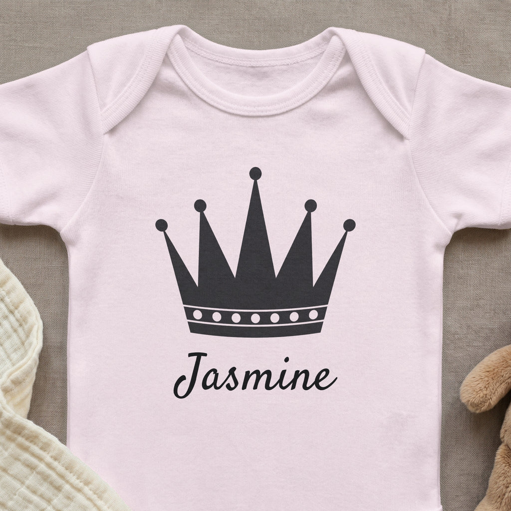 Pink baby onesie with a black crown and the name "Jasmine".