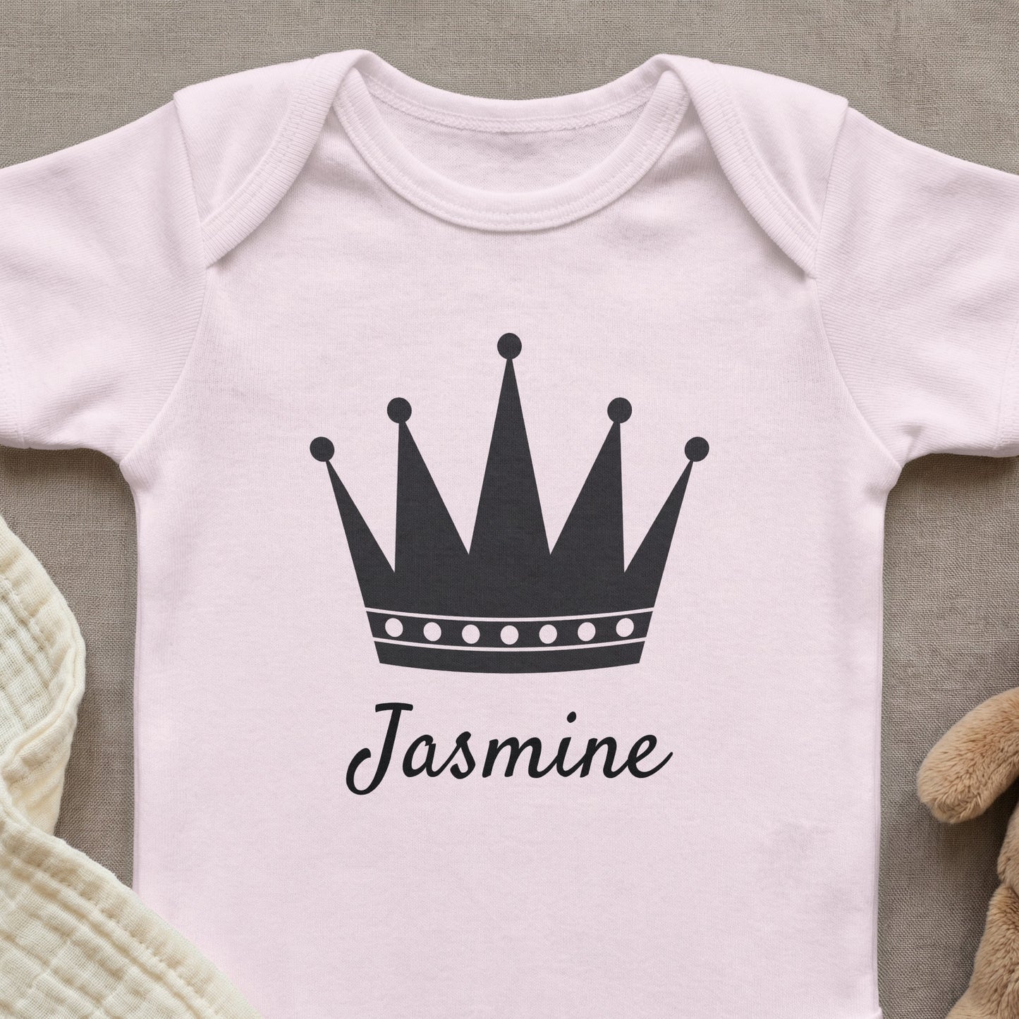 Pink baby onesie with a black crown and the name "Jasmine".