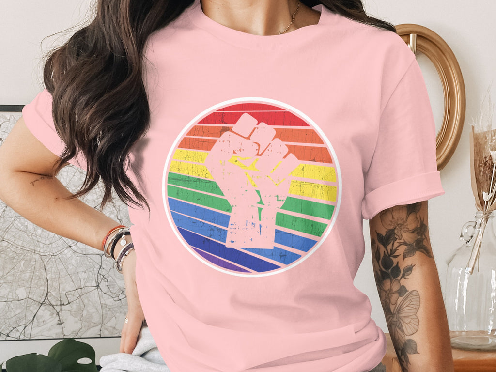 Pink t-shirt featuring a raised fist and rainbow stripes in a circle.