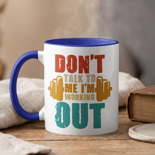 White mug with blue rim, steaming, reads "Don't talk to me I'm working out".
