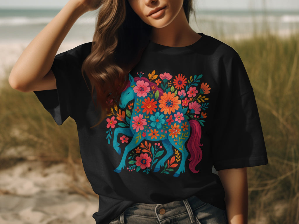 Black t-shirt with a blue unicorn surrounded by colorful flowers and foliage.