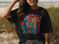 Black t-shirt with a blue unicorn surrounded by colorful flowers and foliage.