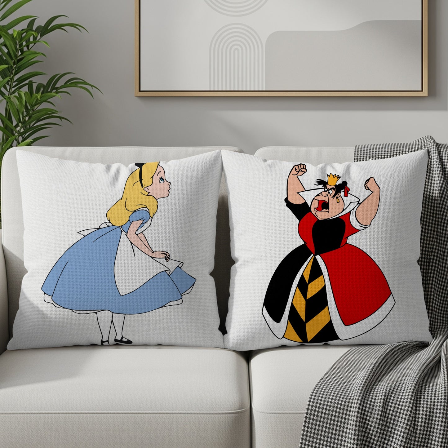 Two toss pillows on a sofa feature cartoon depictions of Alice and the Queen of Hearts.