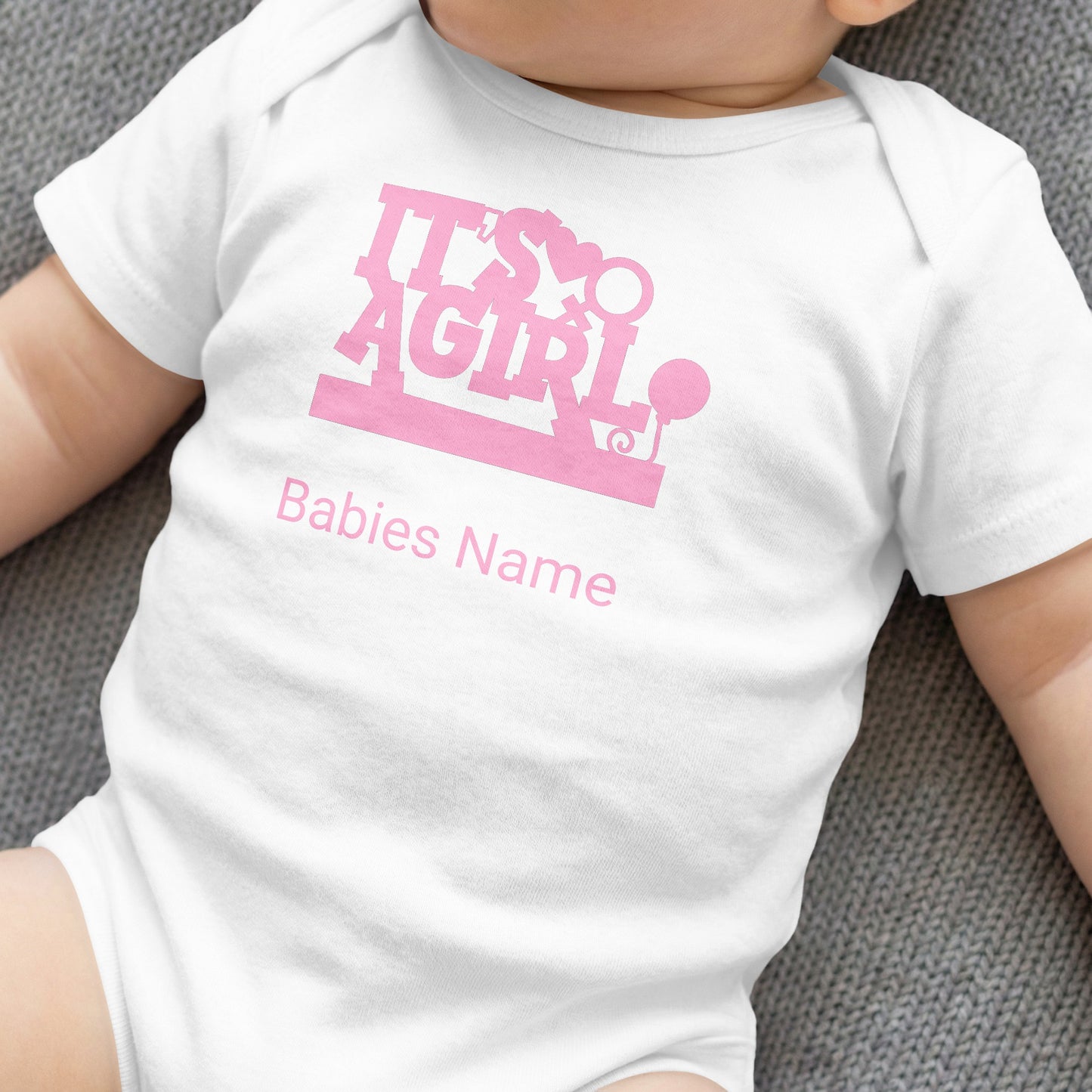 White baby onesie with "It's a girl" text and placeholder for baby's name.