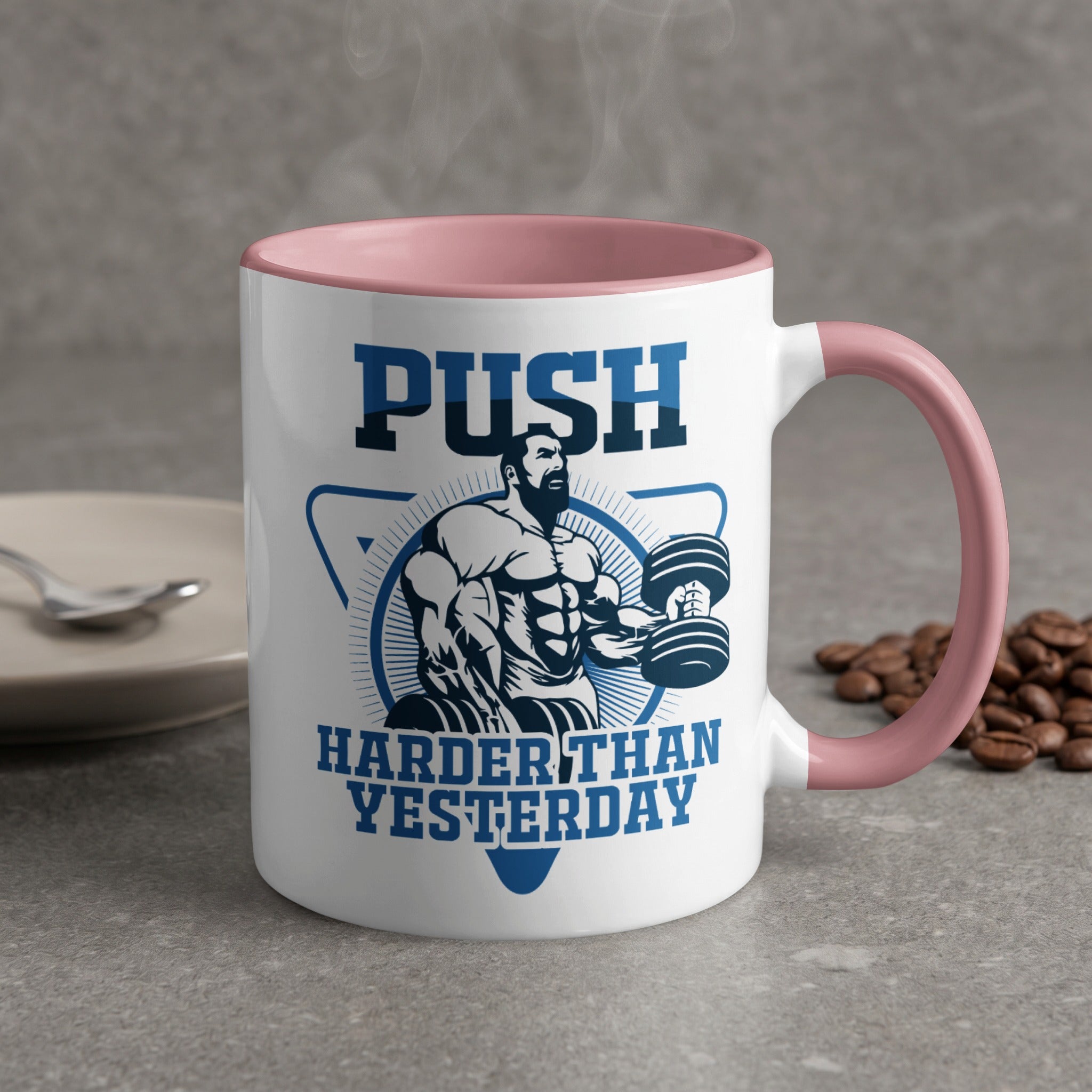 White mug with pink handle, "PUSH HARDER THAN YESTERDAY" and weightlifter illustration.