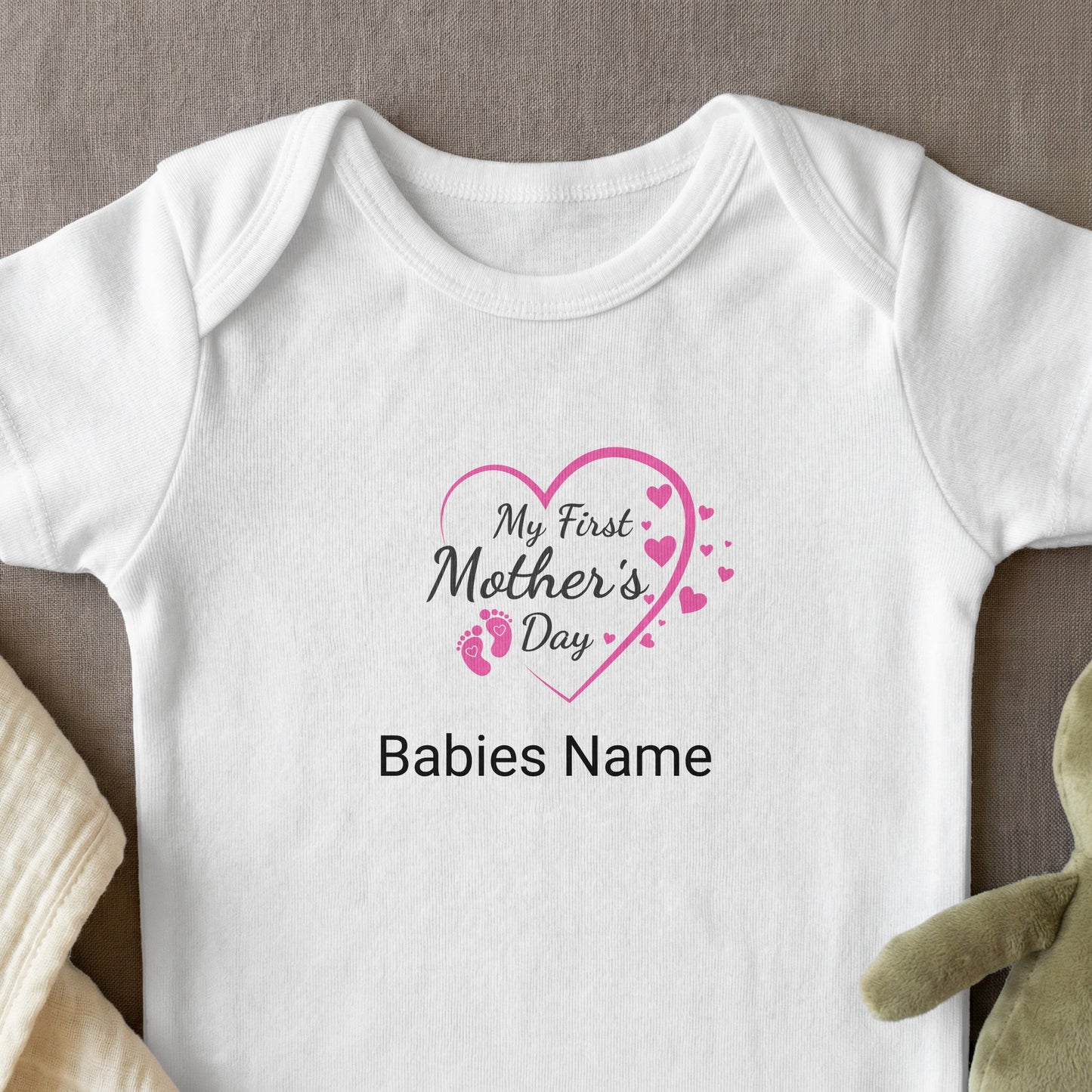 White baby onesie with "My First Mother's Day" and baby footprints.