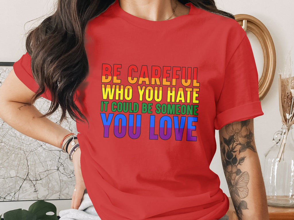 Red t-shirt with "Be careful who you hate it could be someone you love" text in rainbow colors.