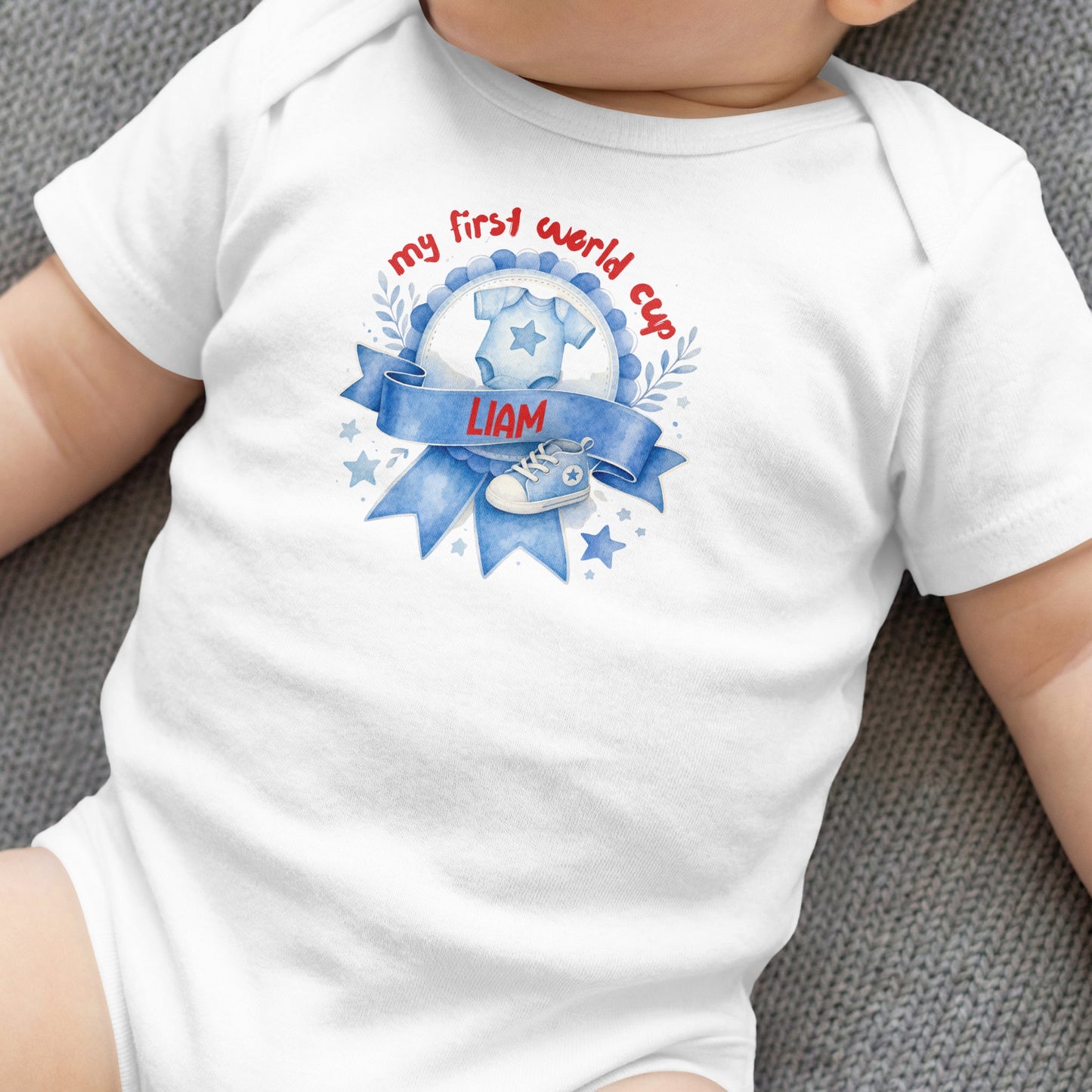 White baby onesie with "my first world cup" text and baby boy's name.