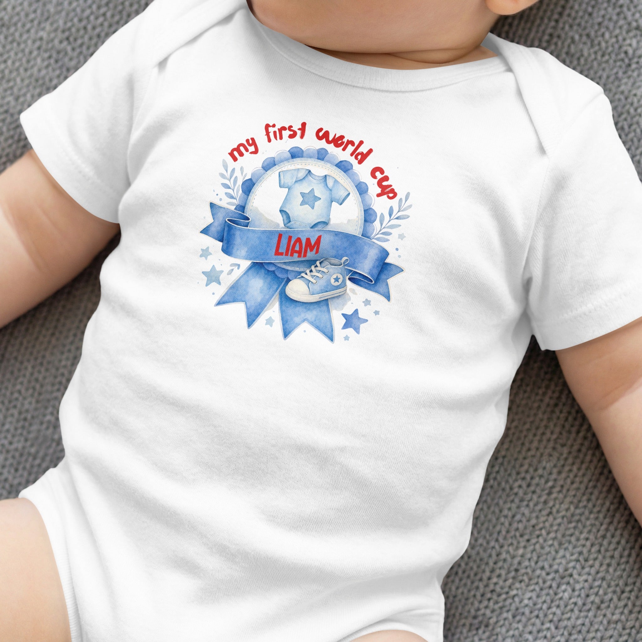 White baby onesie with "my first world cup" text and baby boy's name.