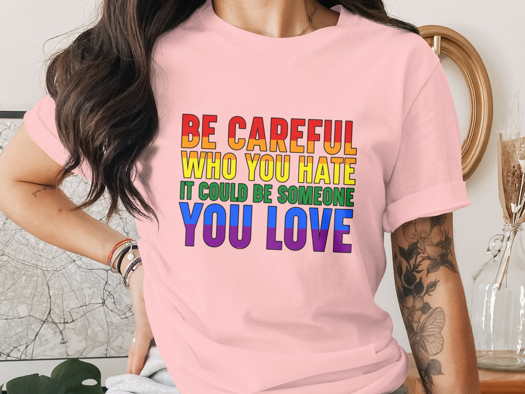 Pink T-shirt with rainbow text: "Be Careful Who You Hate It Could Be Someone You Love."