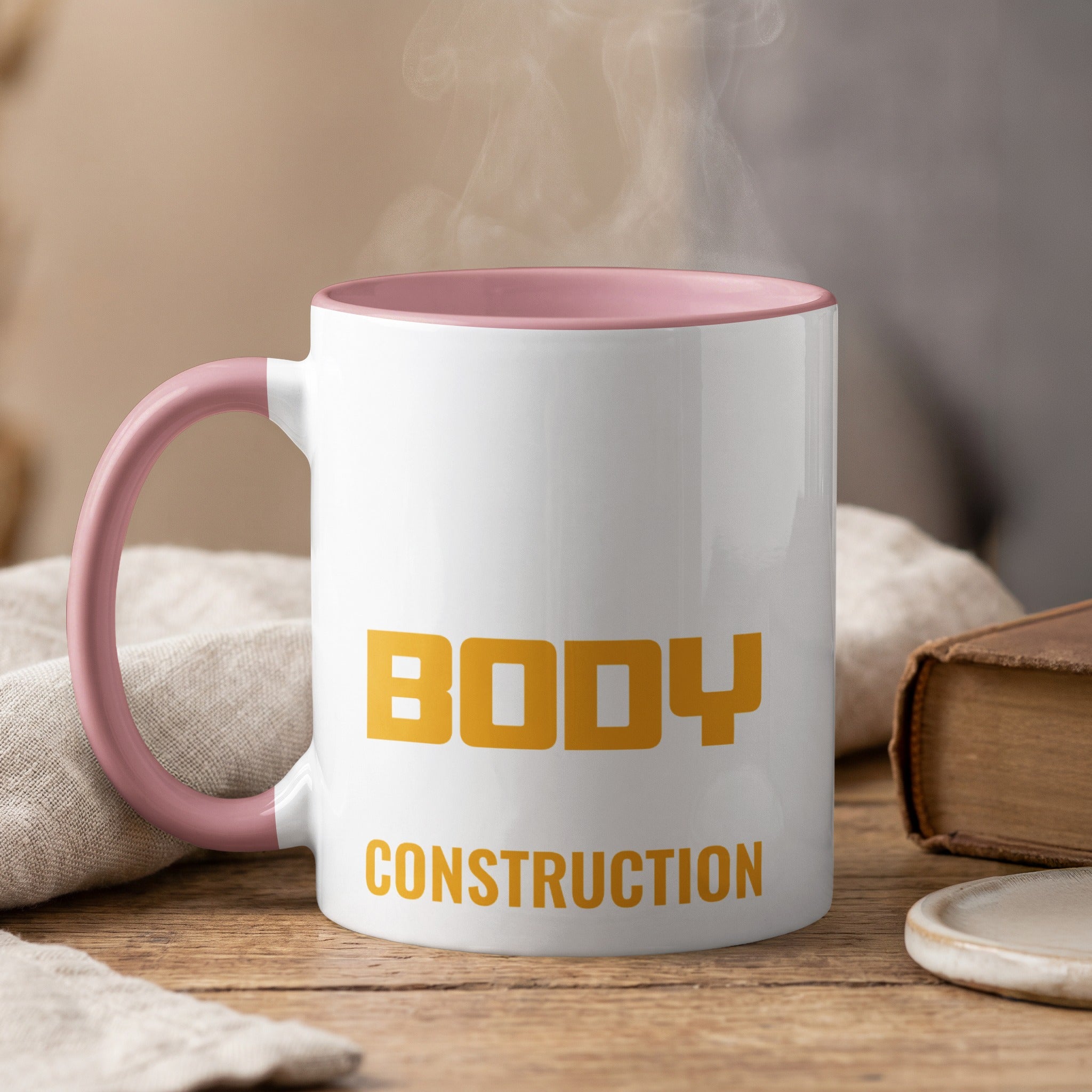 White mug with pink handle, "BODY CONSTRUCTION" in yellow text.