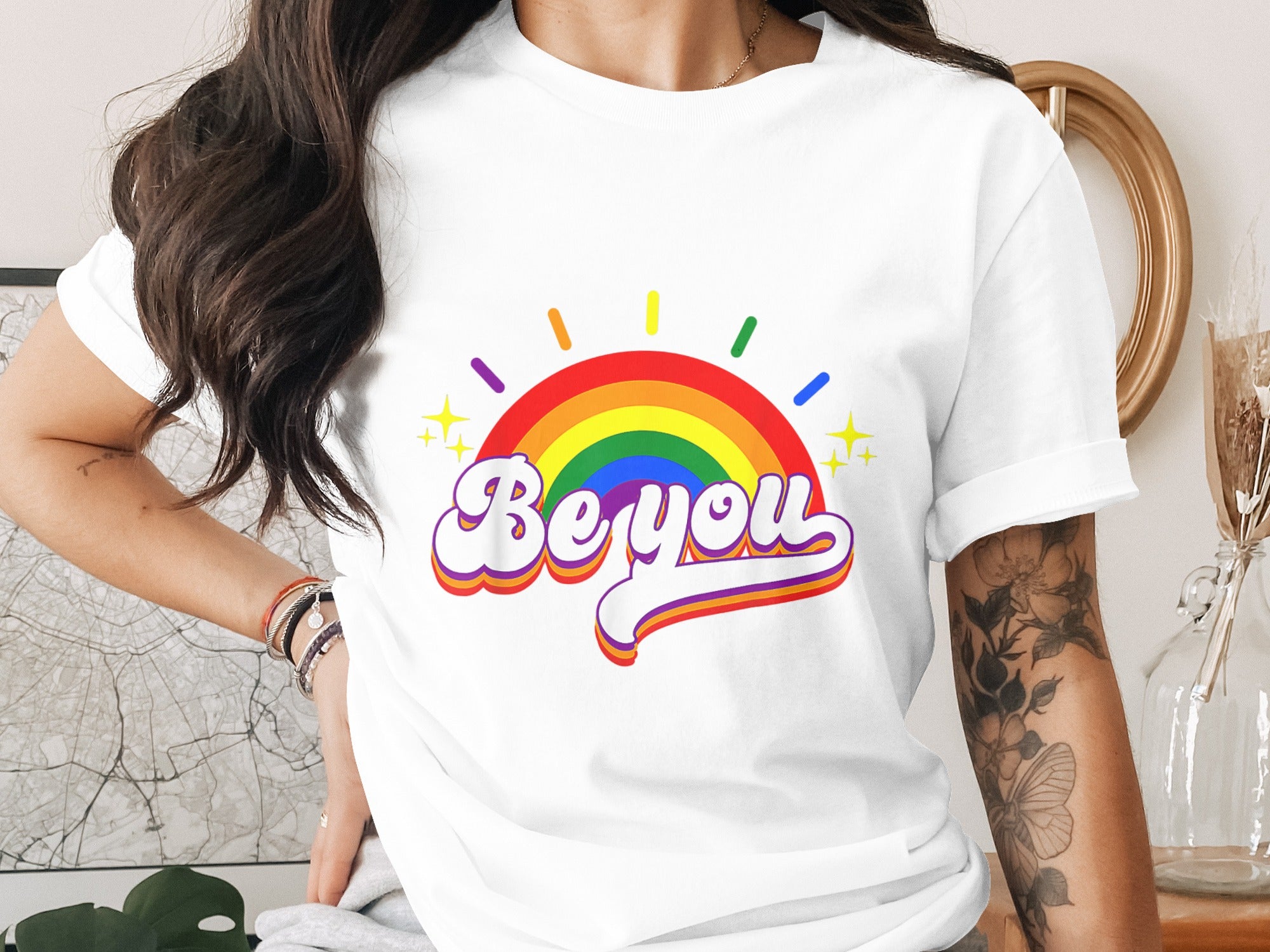 White t-shirt with rainbow, stars, and text "Be you" graphic.