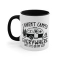 White mug with black handle and interior, featuring camping graphic and text.