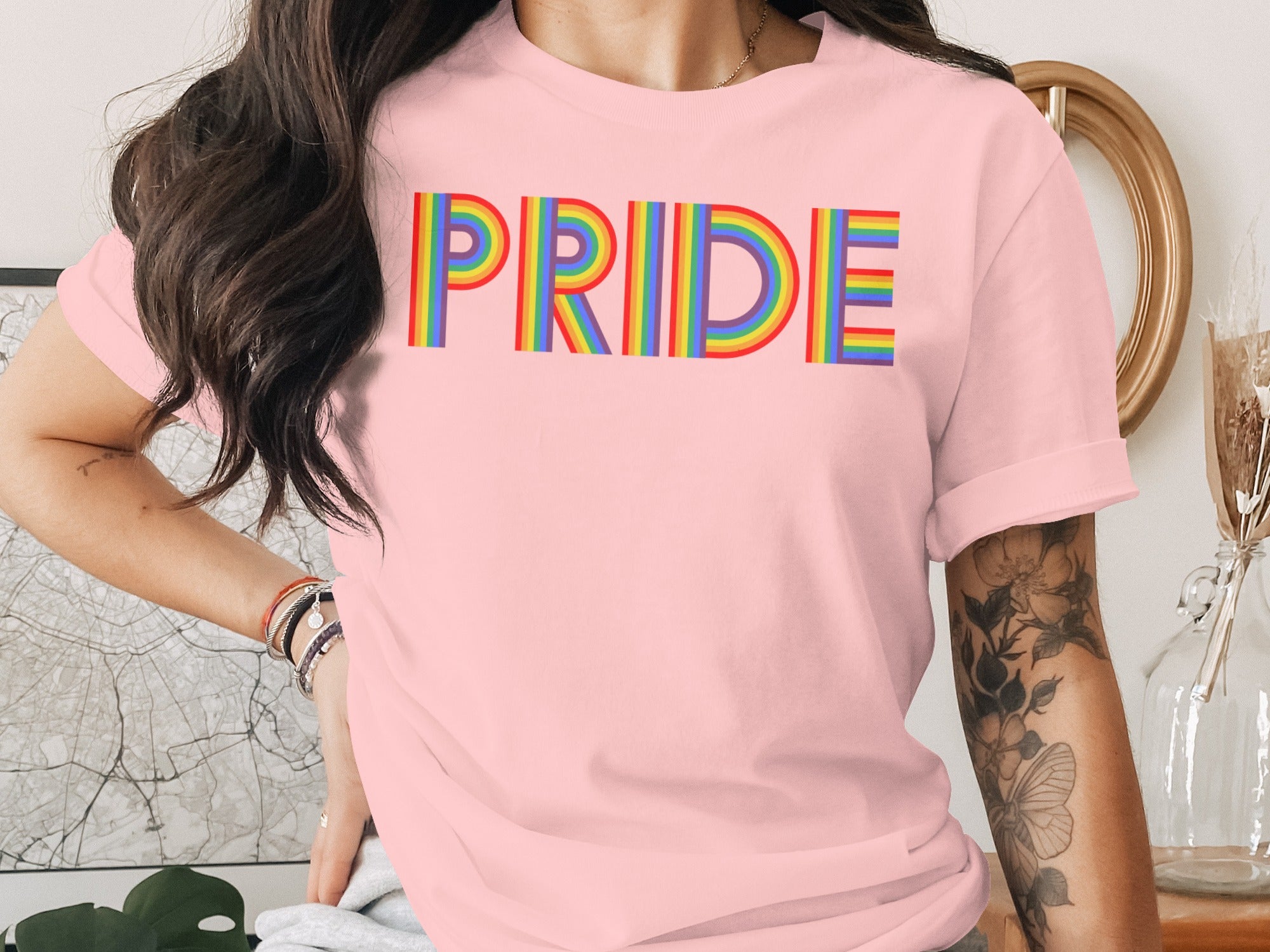 Pink t-shirt with rainbow "PRIDE" text and floral arm tattoo
