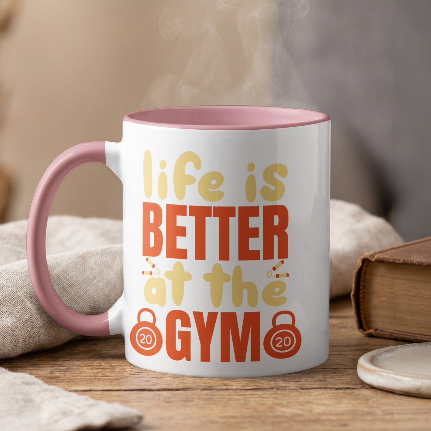 White mug with pink rim, says "life is BETTER at the GYM" with dumbbell graphics.