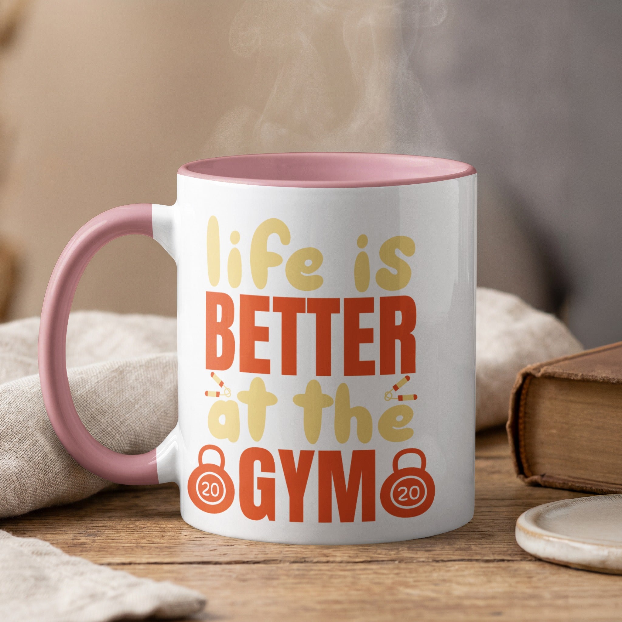 White mug with pink rim, says "life is BETTER at the GYM" with dumbbell graphics.