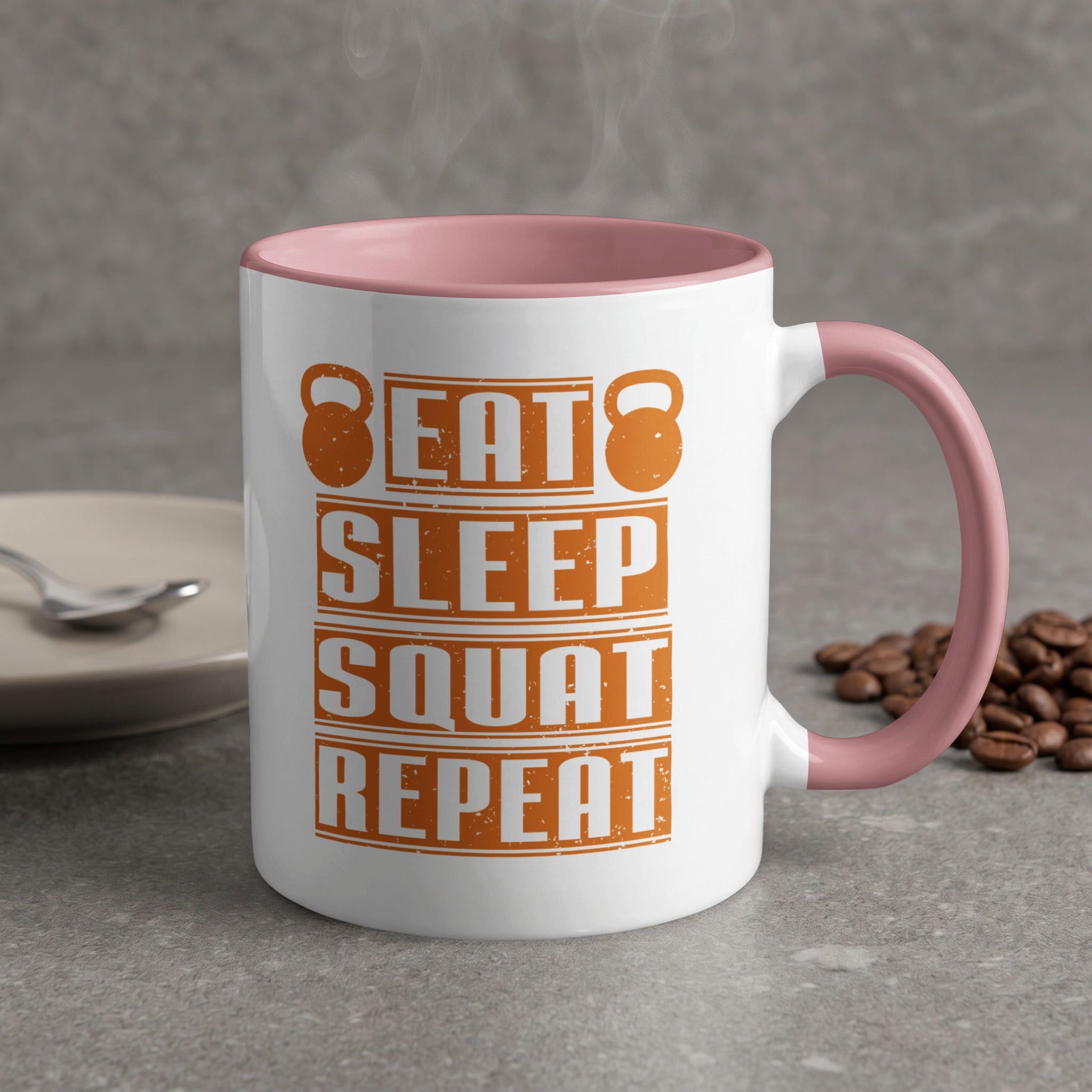 White mug with pink handle, "Eat Sleep Squat Repeat" text, and kettlebell graphics.