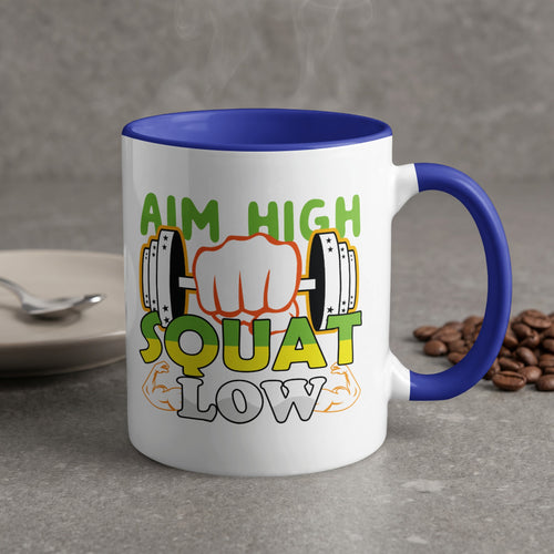 White mug with blue handle, "Aim High Squat Low" text and dumbbell graphics.