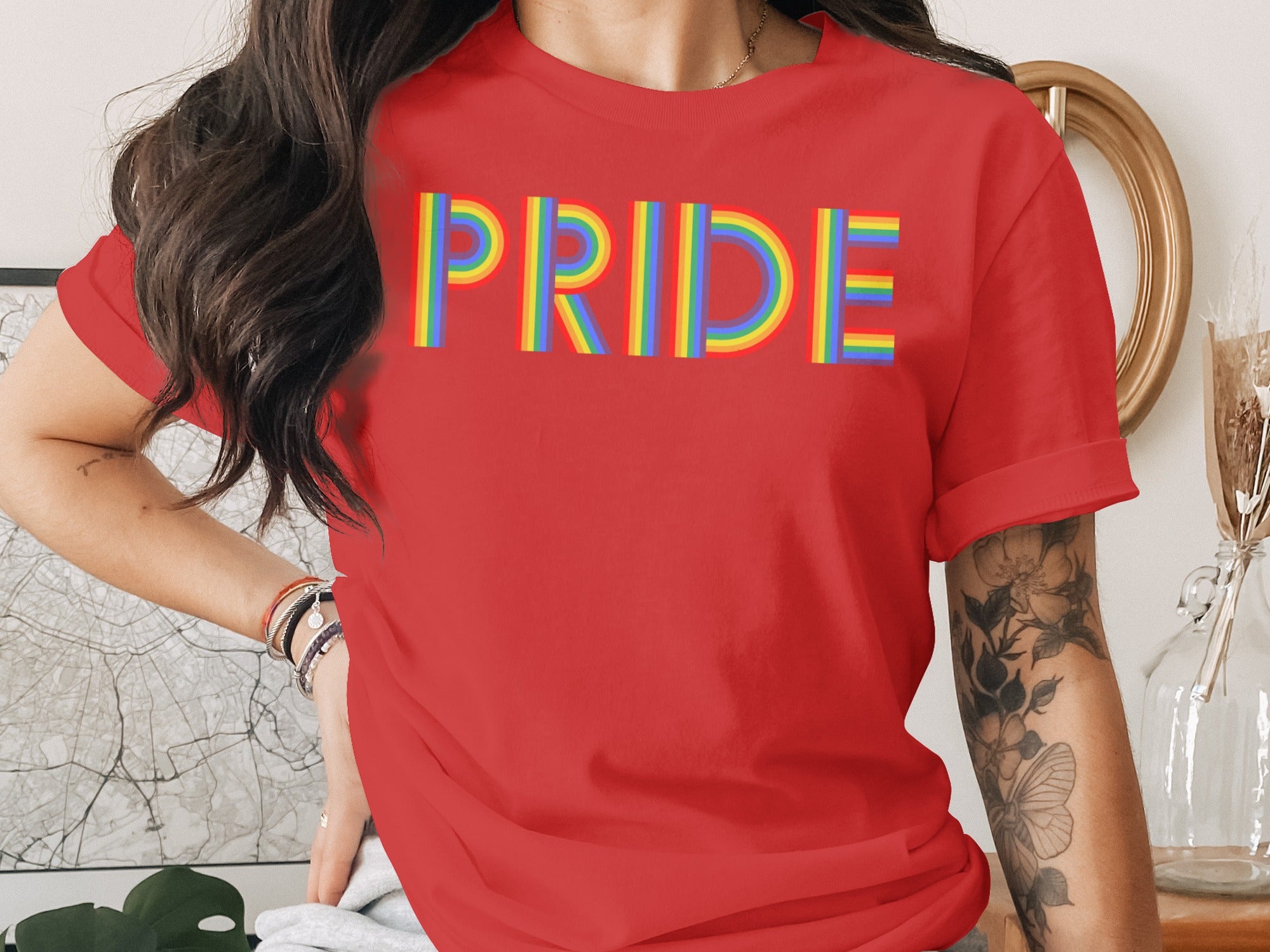 Red t-shirt with rainbow "PRIDE" text and arm tattoos.