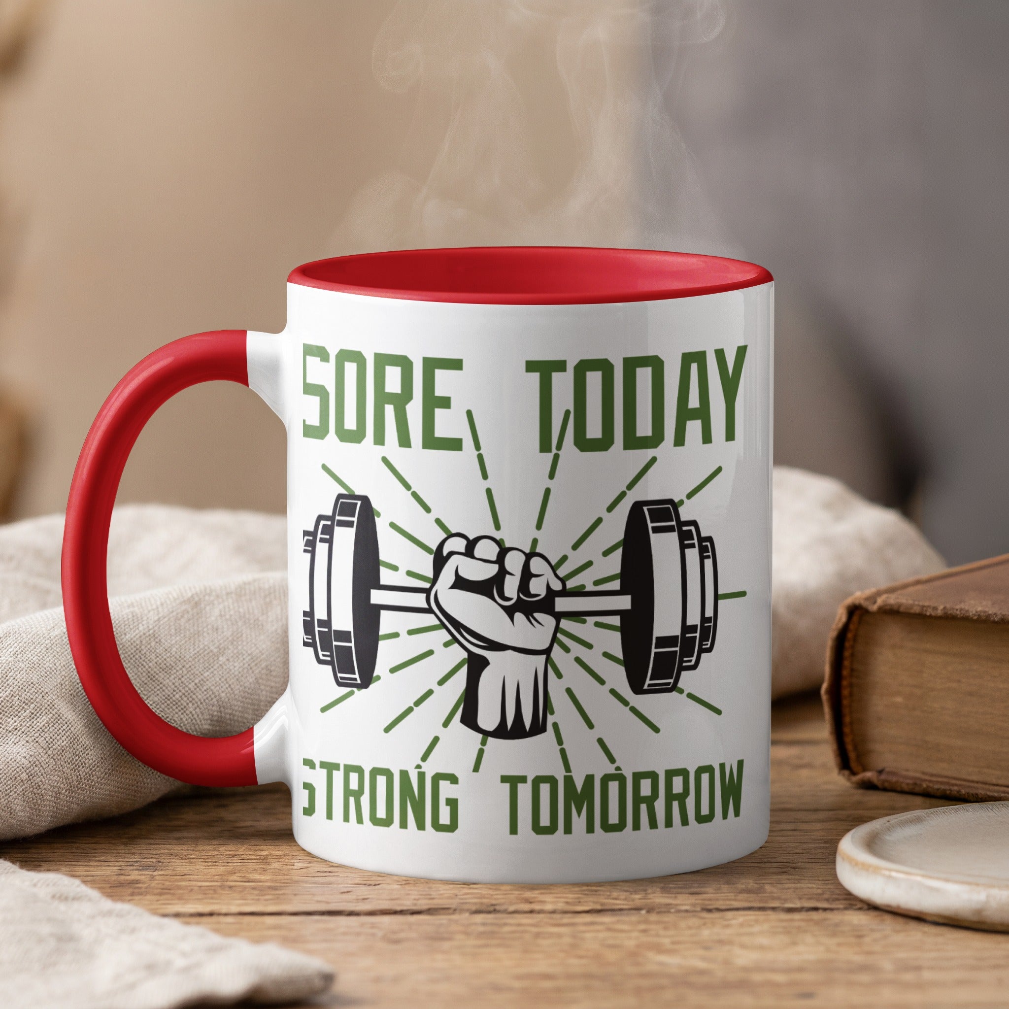 White mug with red rim and handle, featuring a fist holding a dumbbell and text.