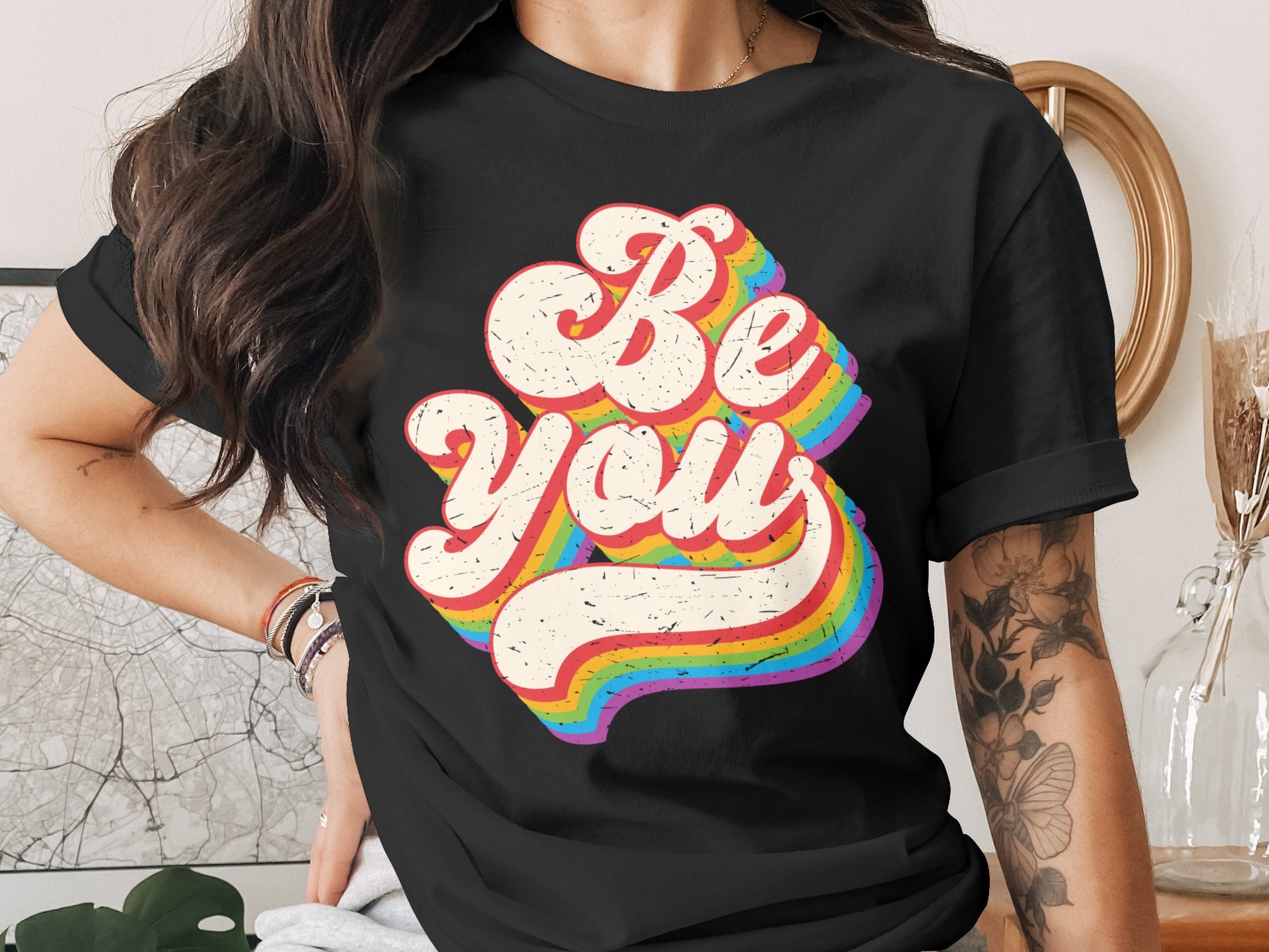Black t-shirt with retro "Be You" text and rainbow stripe effect.