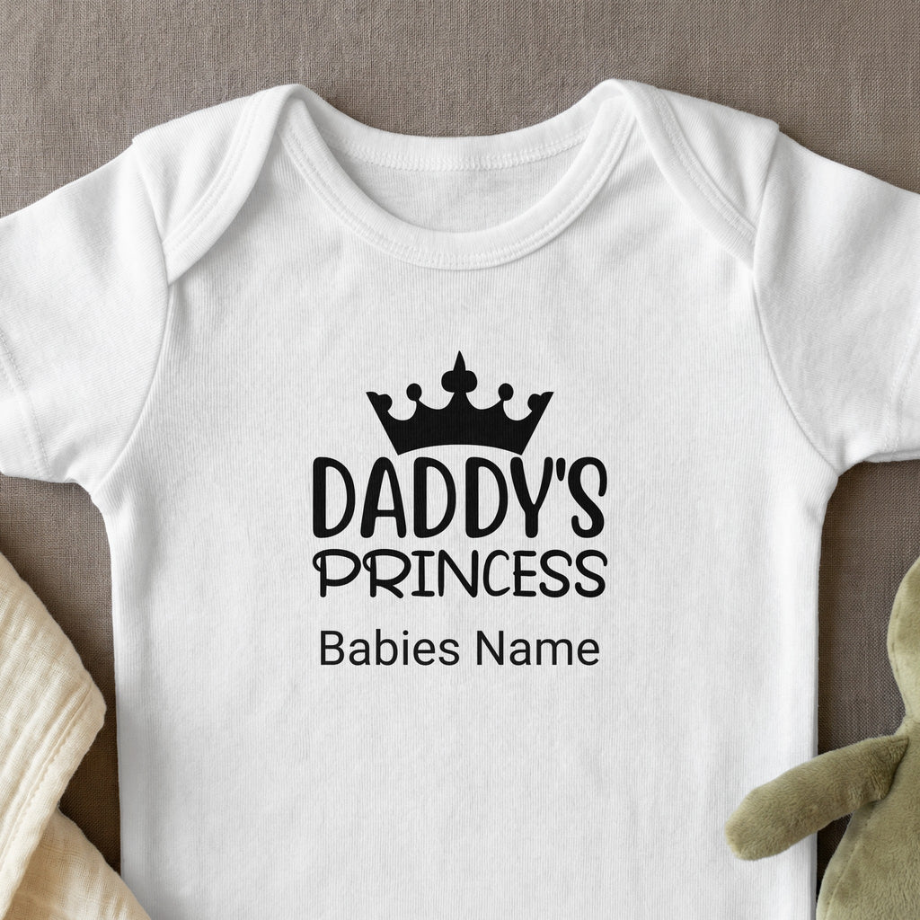 White baby onesie with "Daddy's Princess" and a crown graphic.