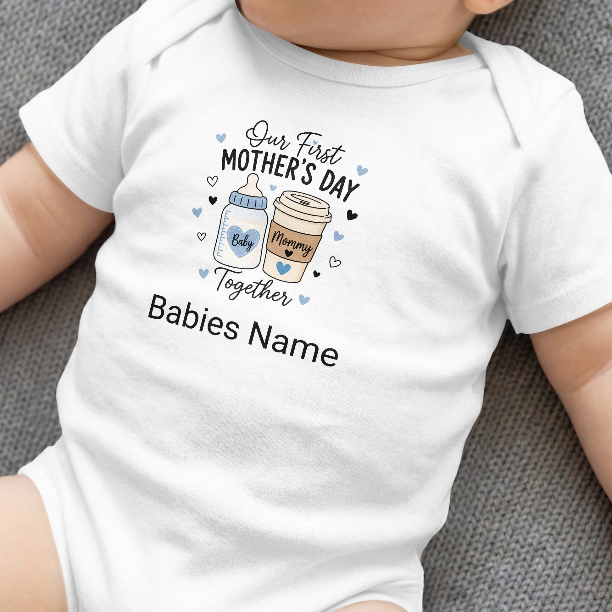 White baby bodysuit with "Our First Mother's Day" text and cartoon coffee and baby bottles.