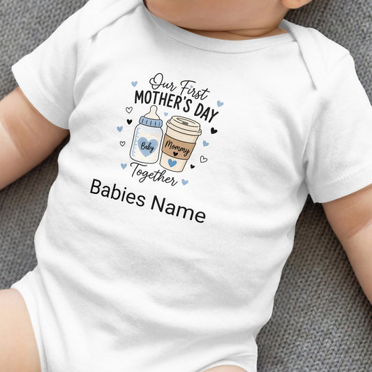 White baby bodysuit with "Our First Mother's Day" text and cartoon coffee and baby bottles.