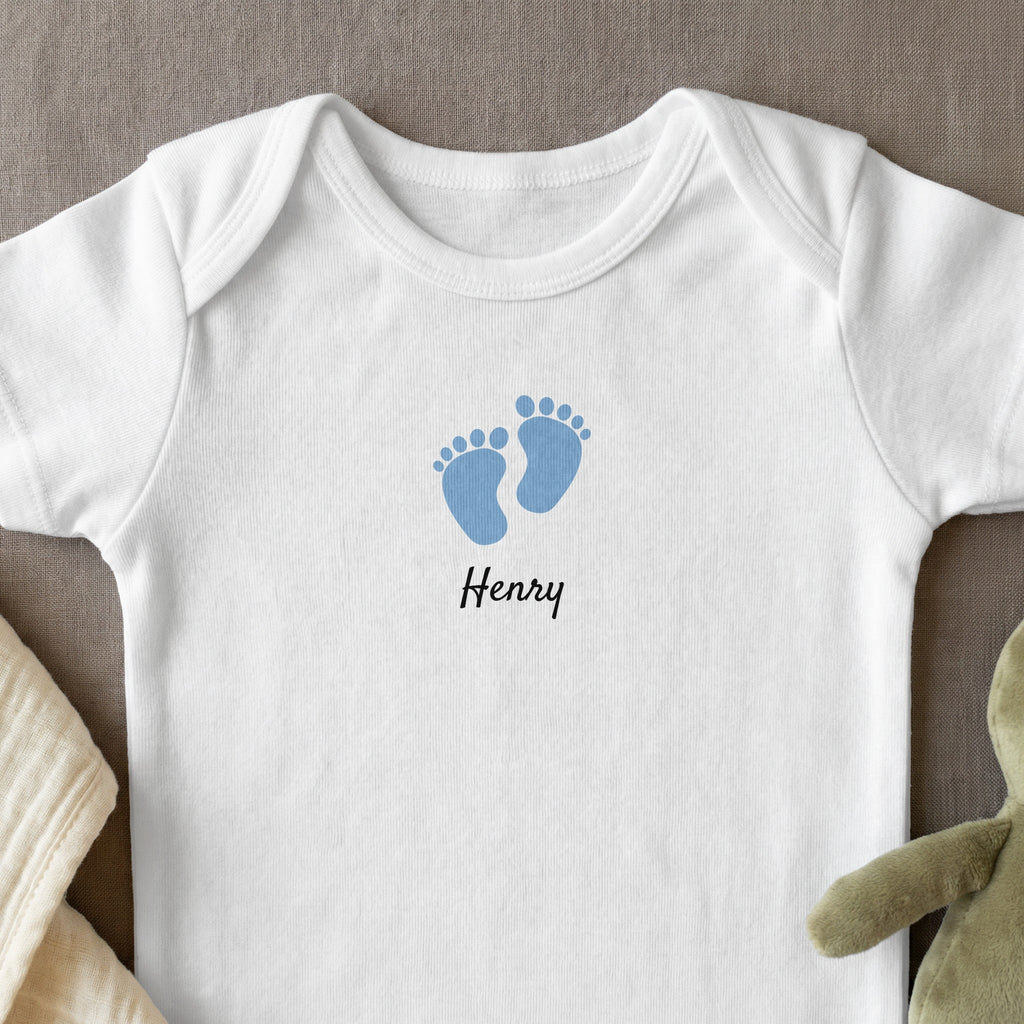 White baby bodysuit with blue footprints and "Henry" text.