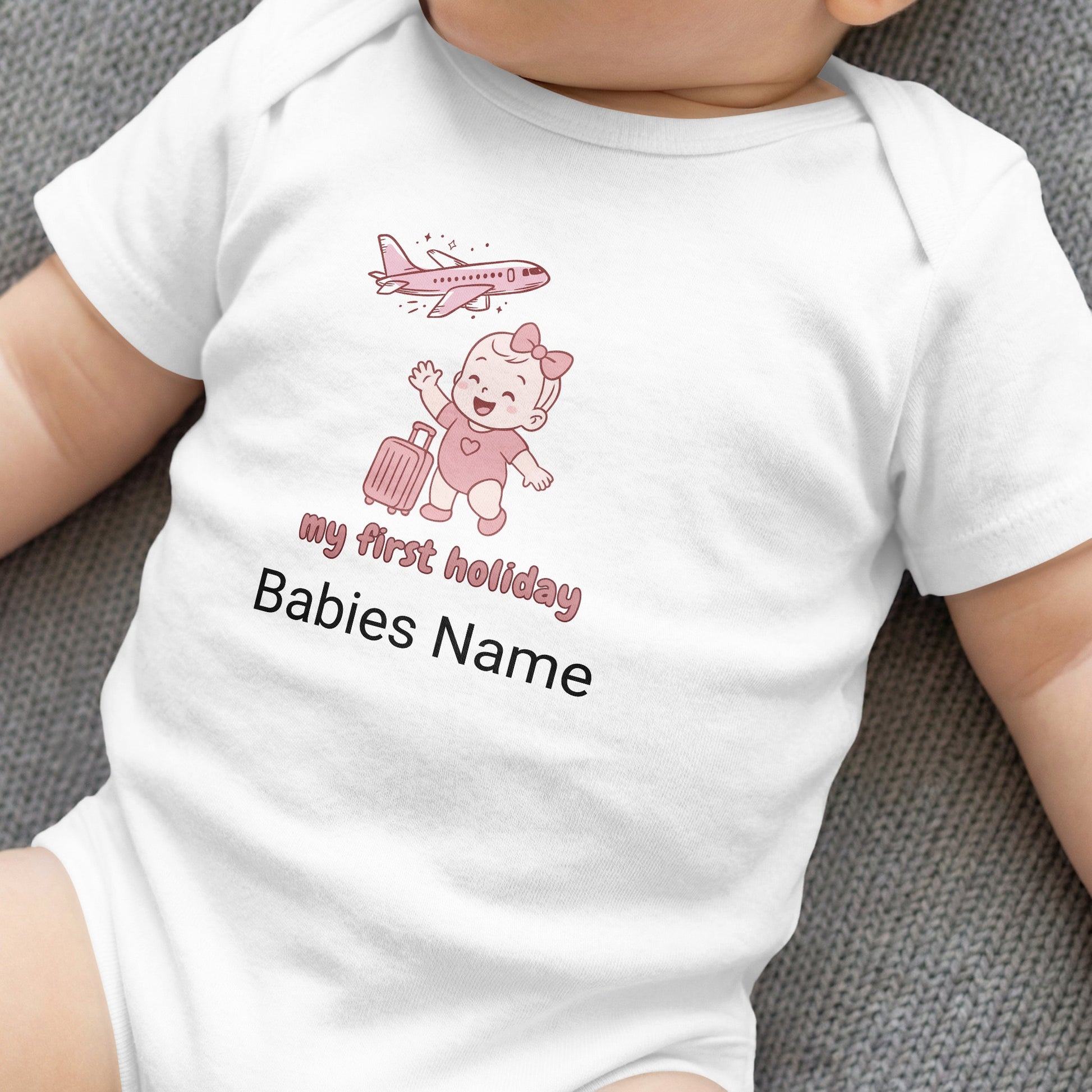 White baby bodysuit with "my first holiday" and cartoon plane and baby.