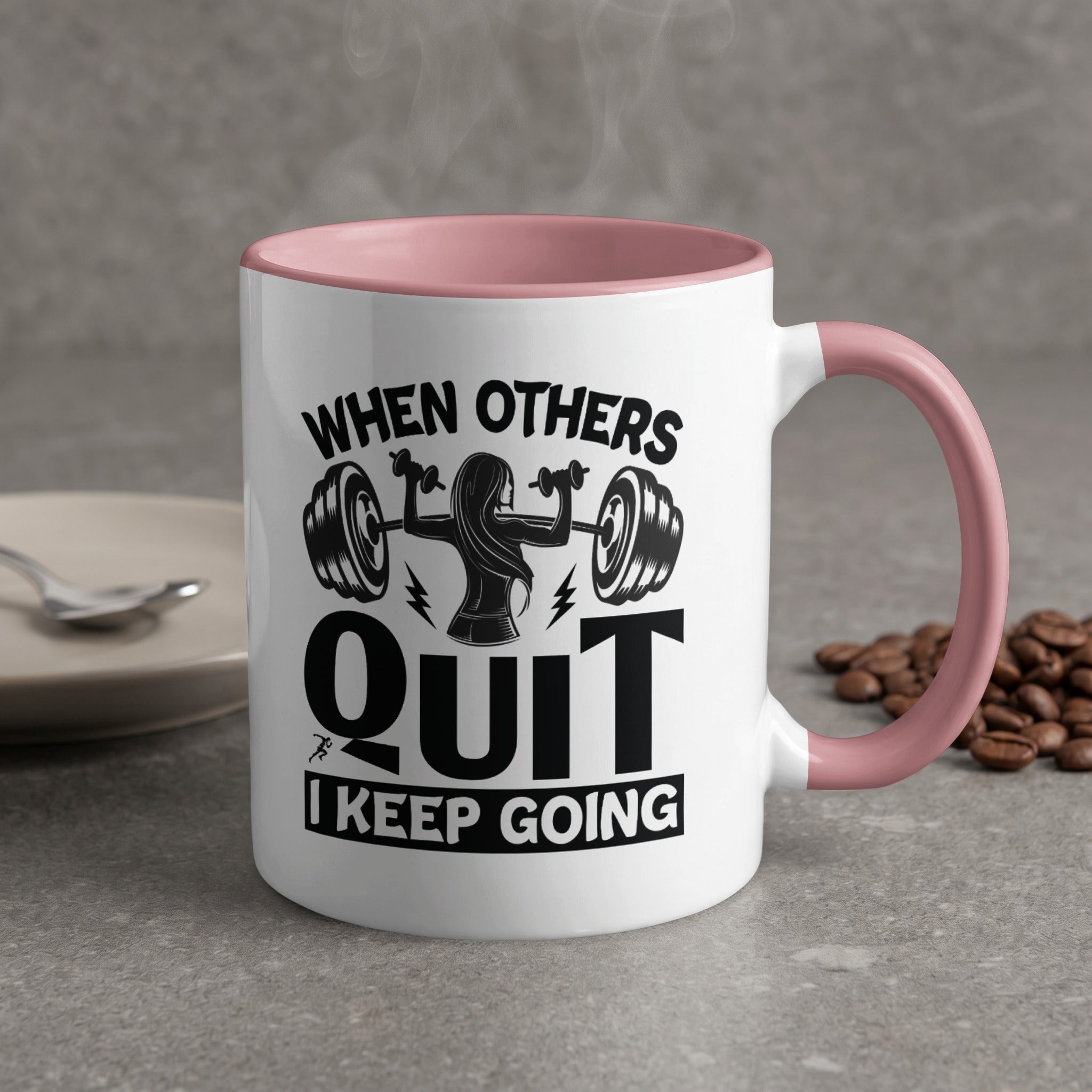 White mug with pink handle, featuring a motivational quote and barbell graphic.