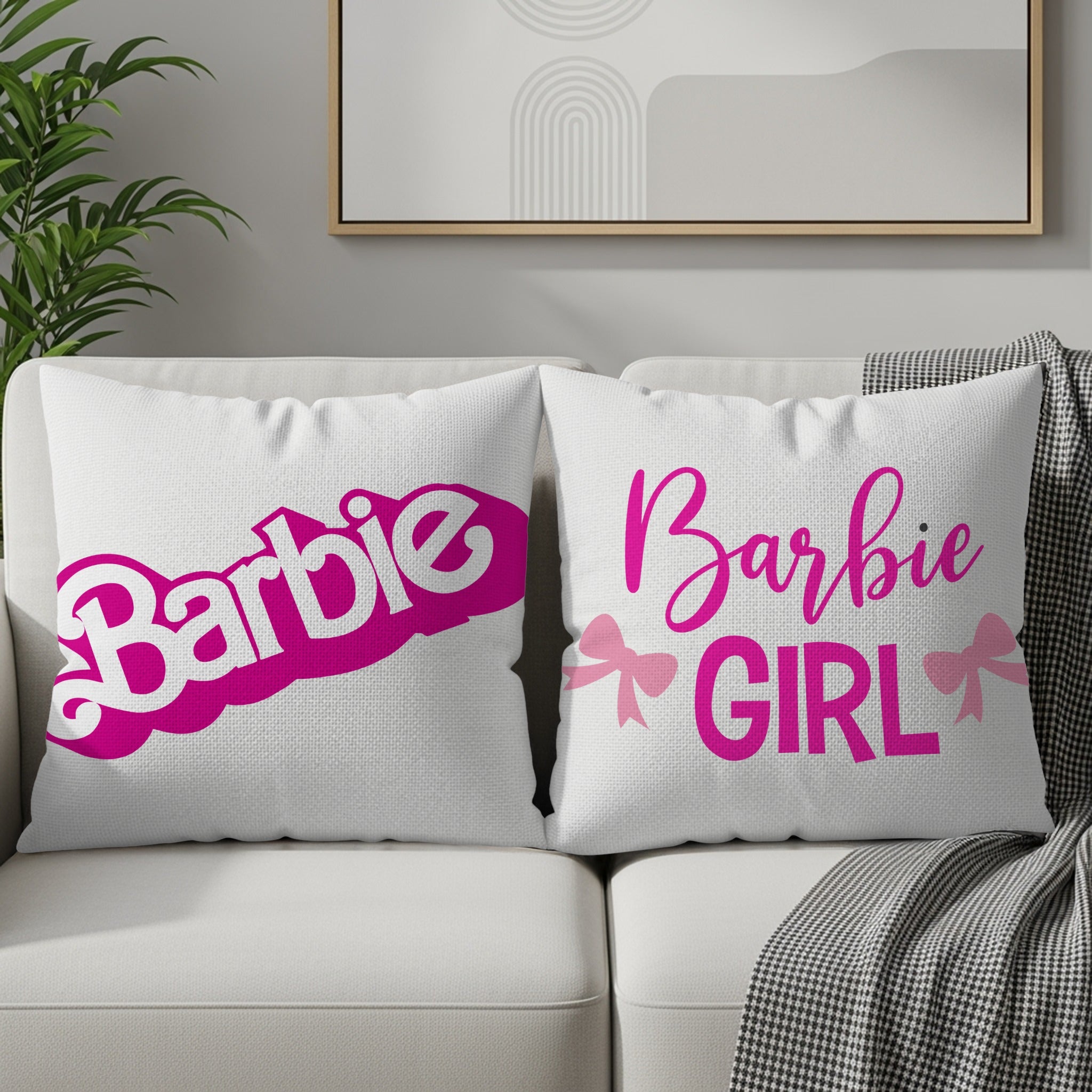 Two white Barbie-themed throw pillows with pink text and bows on a sofa.