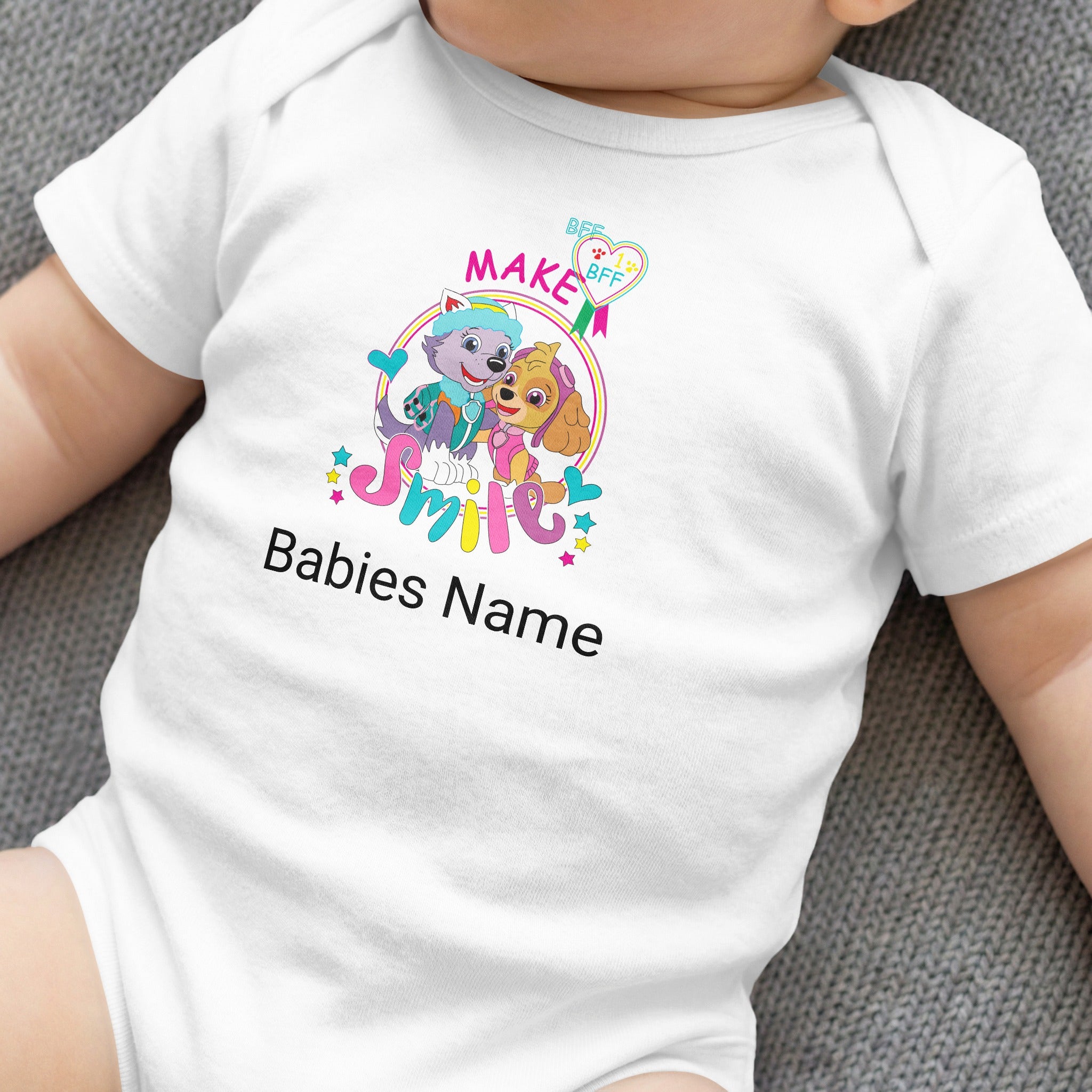 White baby onesie with "MAKE Babies Name SMILE" and cartoon dogs.