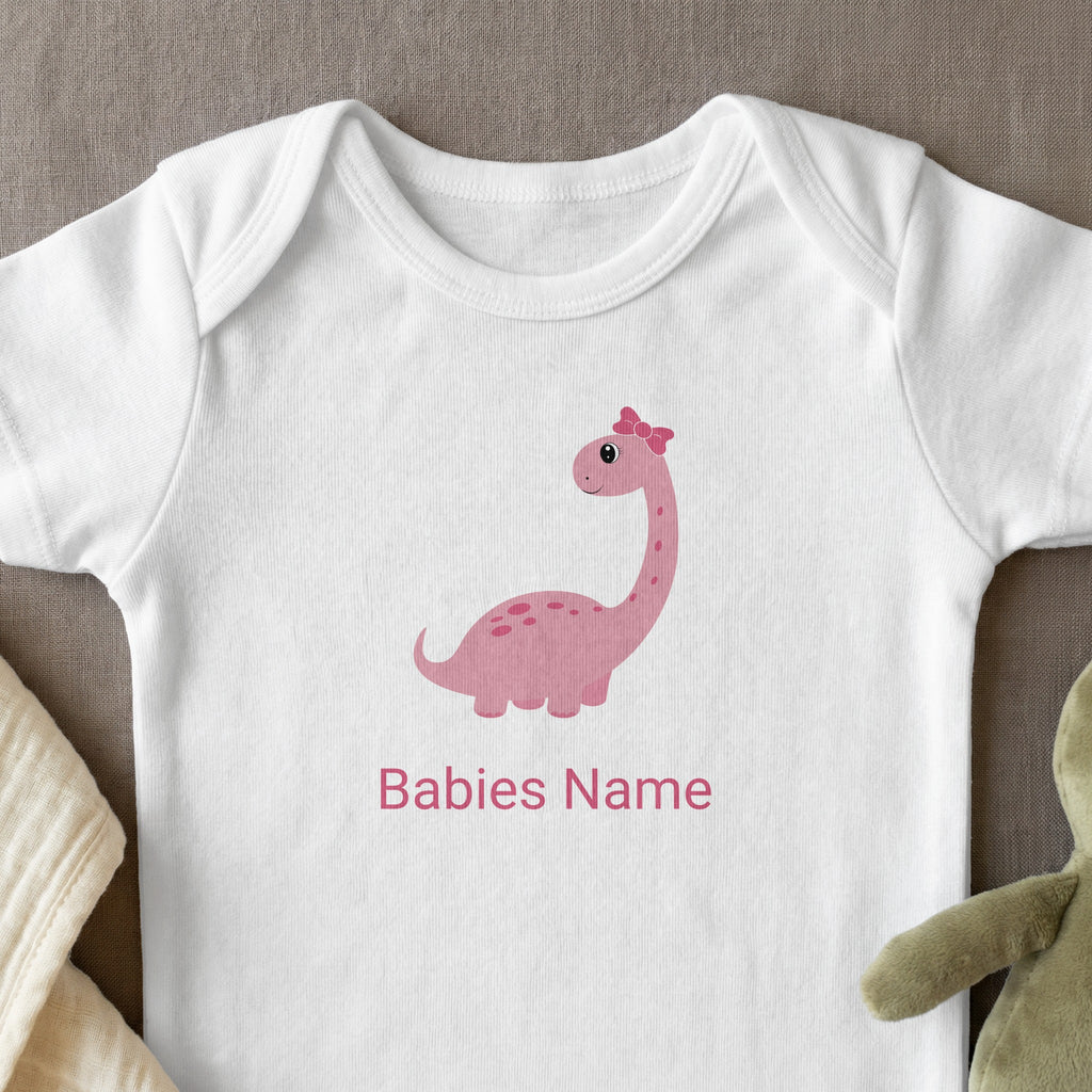 White baby onesie with pink dinosaur graphic and personalized text.