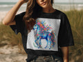 Black t-shirt with a blue, floral unicorn design on a checkered background.