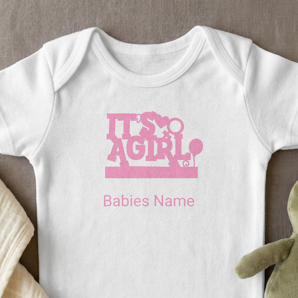 White baby onesie with "It's A Girl" and "Babies Name" text in pink.
