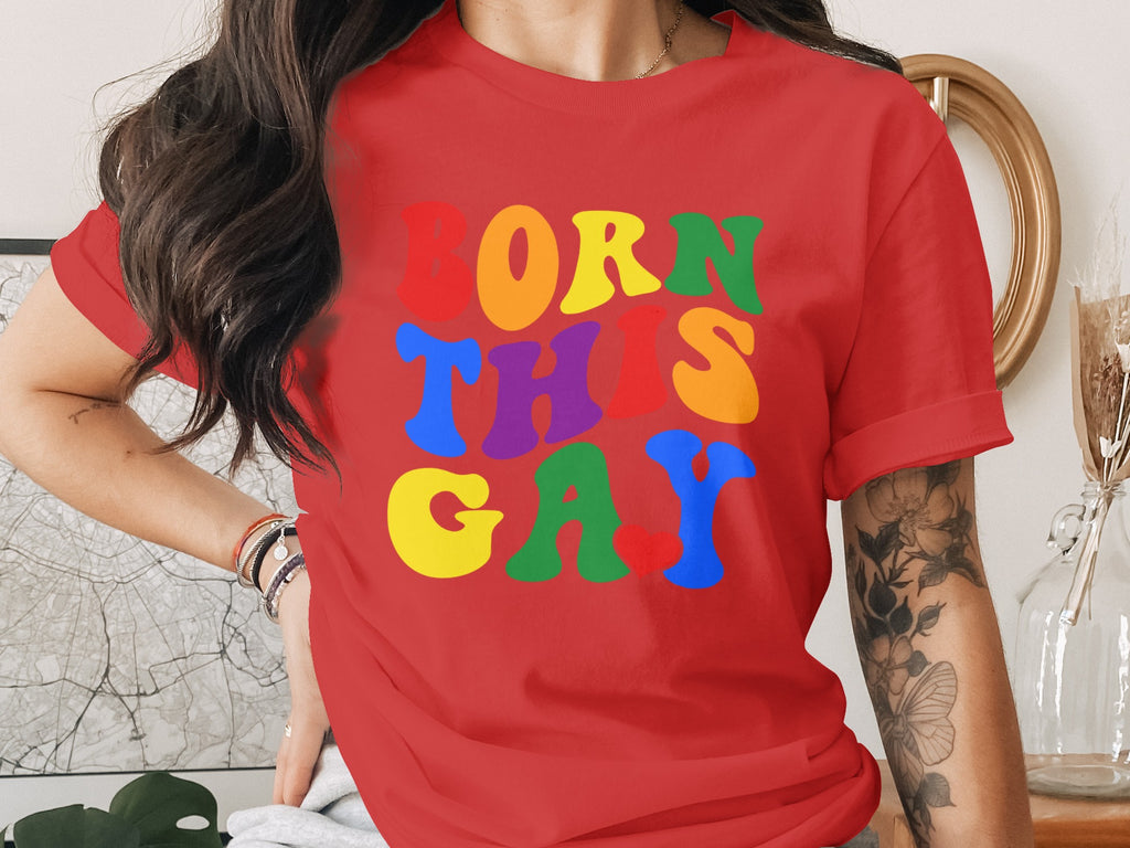 Red t-shirt with colorful "BORN THIS GAY" text in groovy lettering.