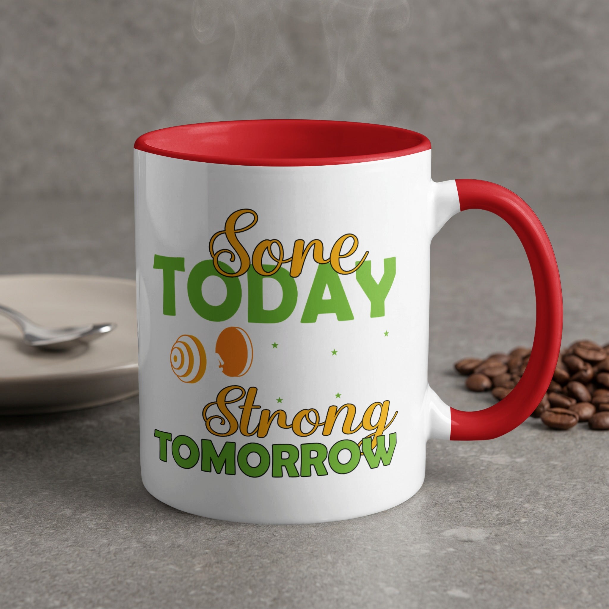 "Sore Today, Strong Tomorrow" text on a red-handled mug with coffee beans.