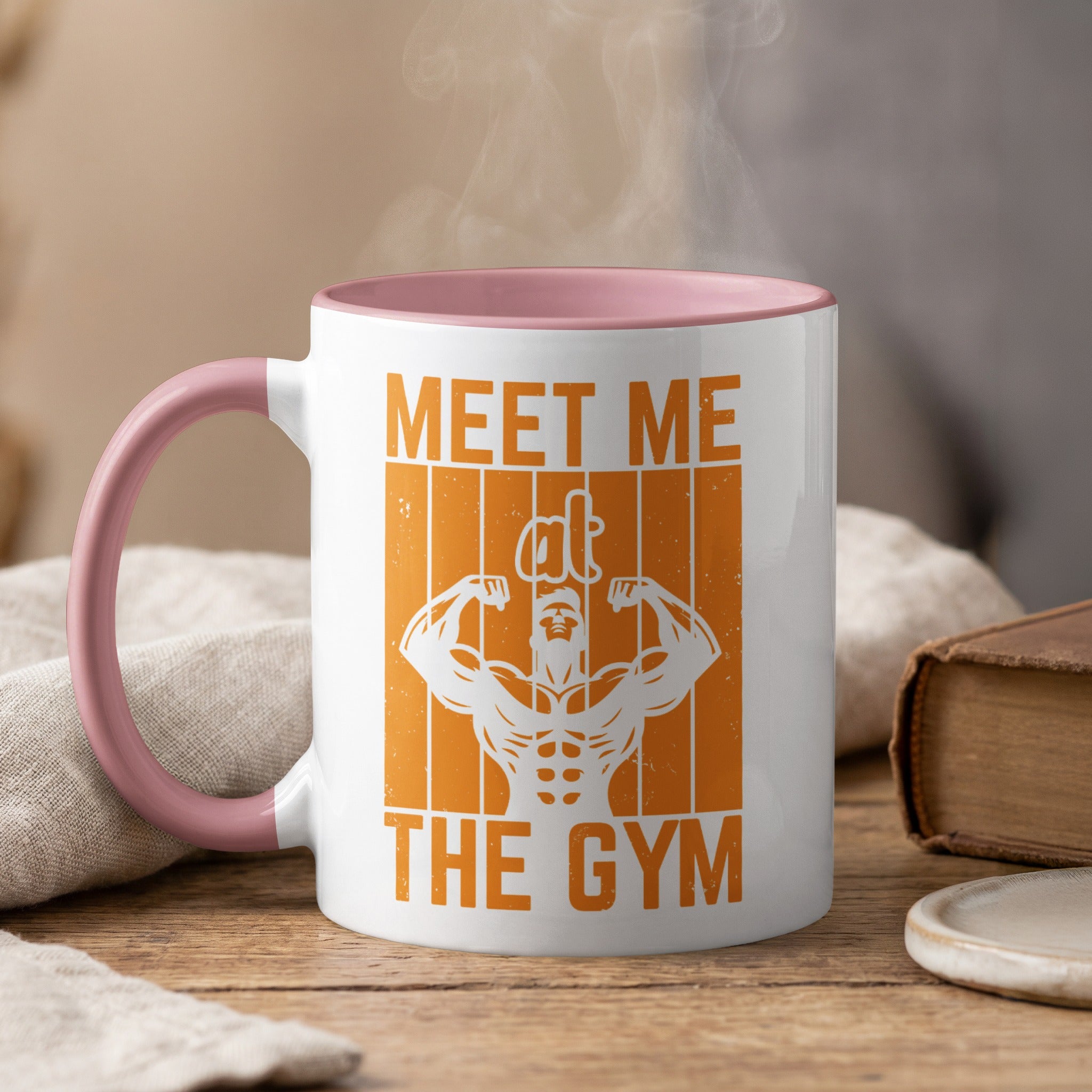 White mug with pink rim, saying "Meet Me The Gym" with muscular graphic.