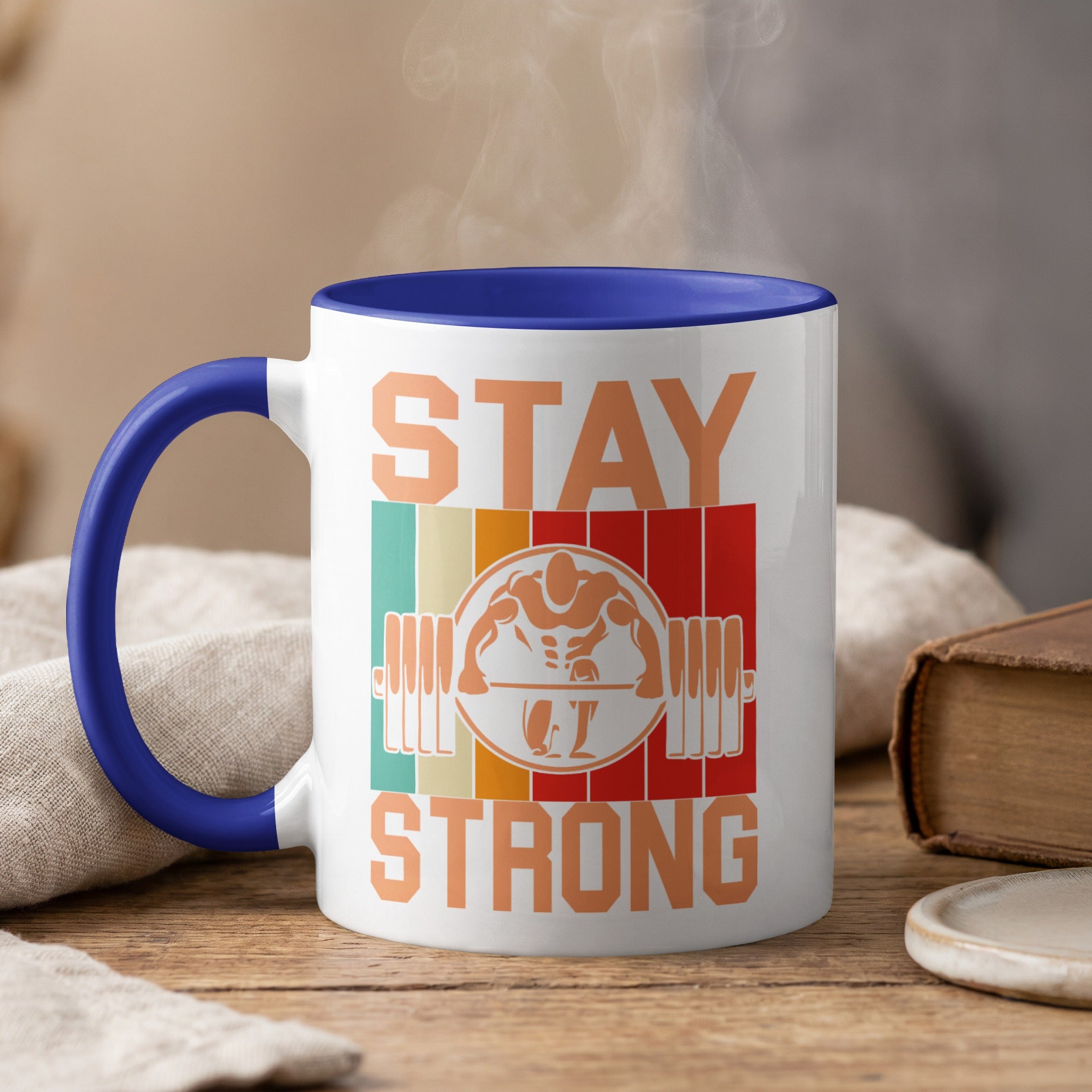 Mug with "STAY STRONG" text and barbell illustration, steaming.