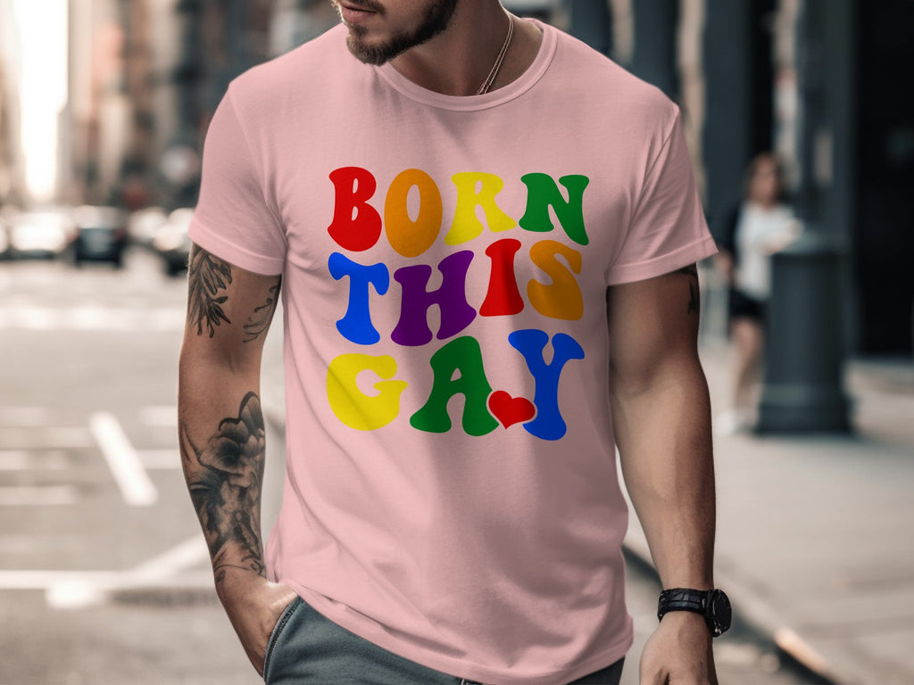 Pink t-shirt with rainbow text that says "BORN THIS GAY" with a red heart.