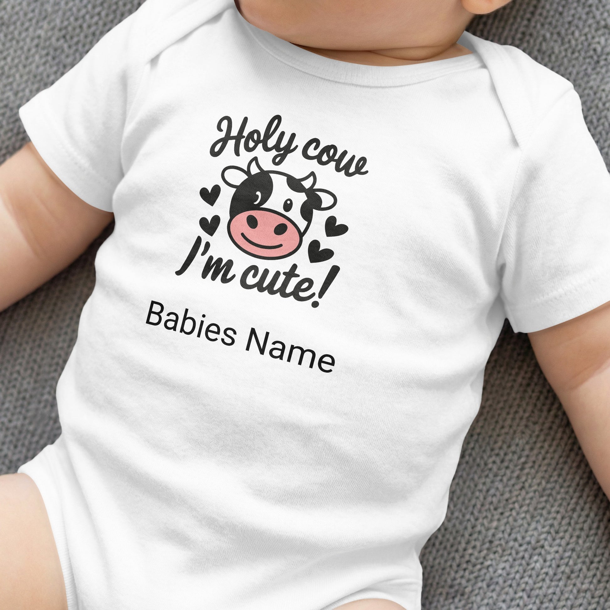 White baby onesie with "Holy cow I'm cute!" and cow design.