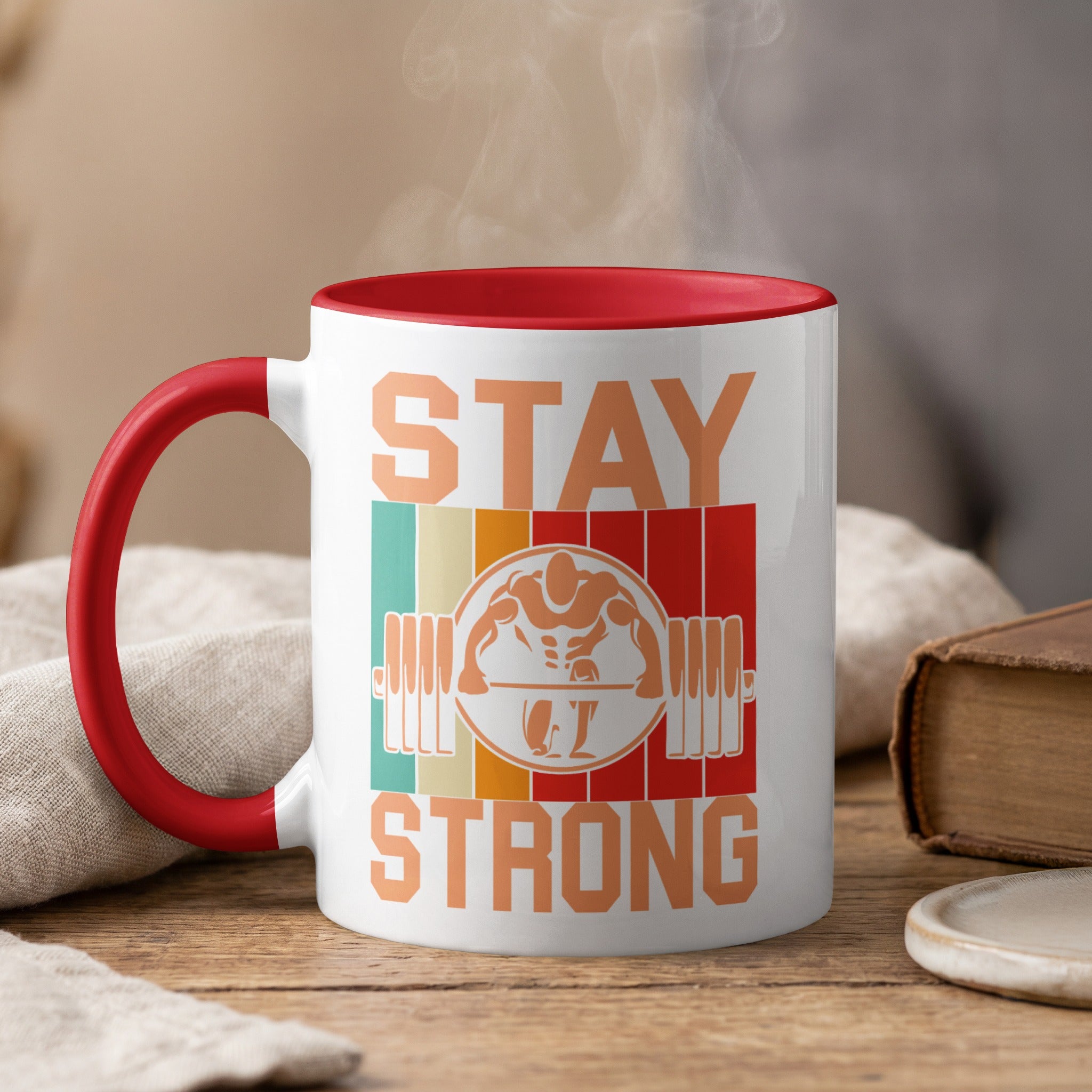 White mug with red rim and handle, featuring "STAY STRONG" text and barbell icon.